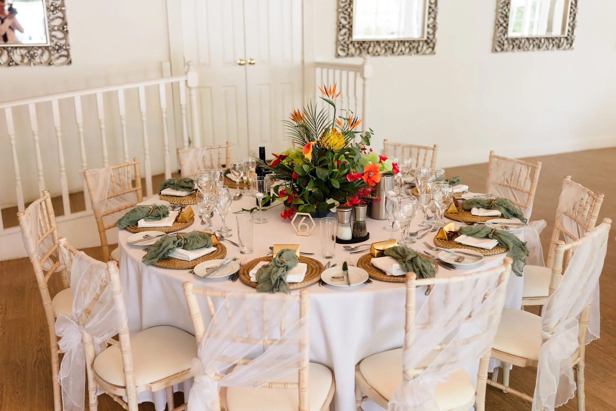 Wedding breakfast table dressed with tropical flowers, rattan chargers and sage napkins at Warwick House