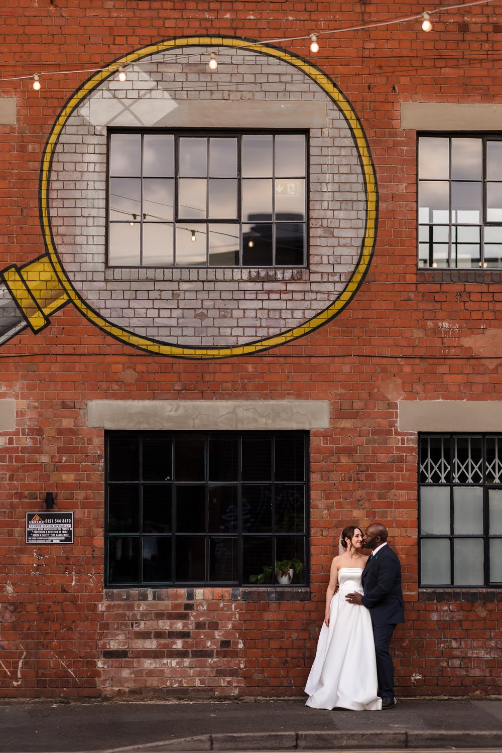 Sometimes the best portraits show the couple in context with their surroundings. This Digbeth industrial building, complete with painted street art and Victorian brick, tells as much of their urban wedding story as a close-up would.