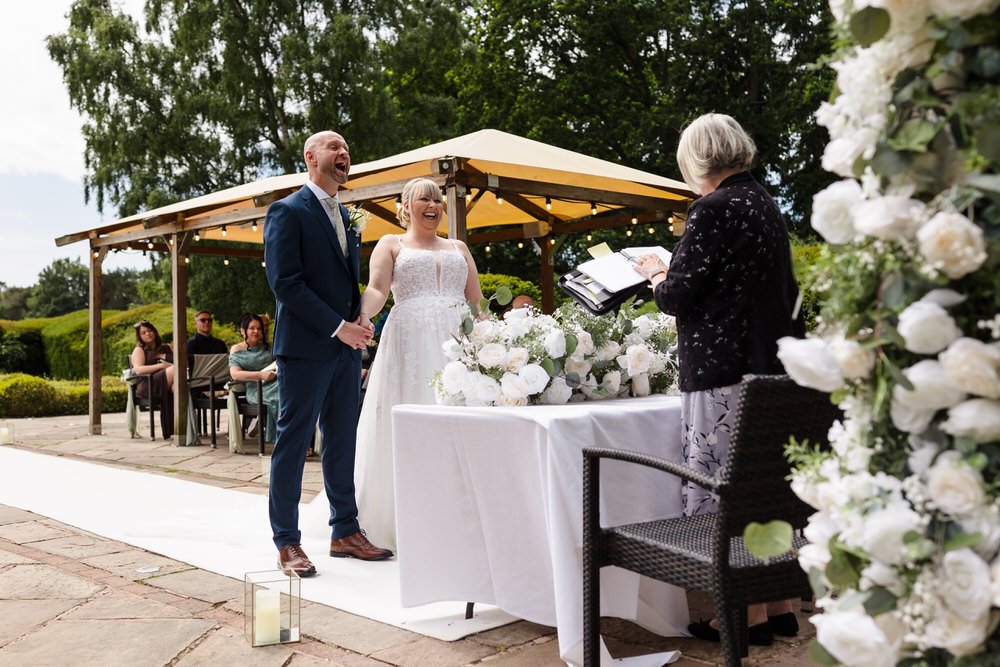 Bride and groom laughing together during their outdoor ceremony at Hogarths Stone Manor