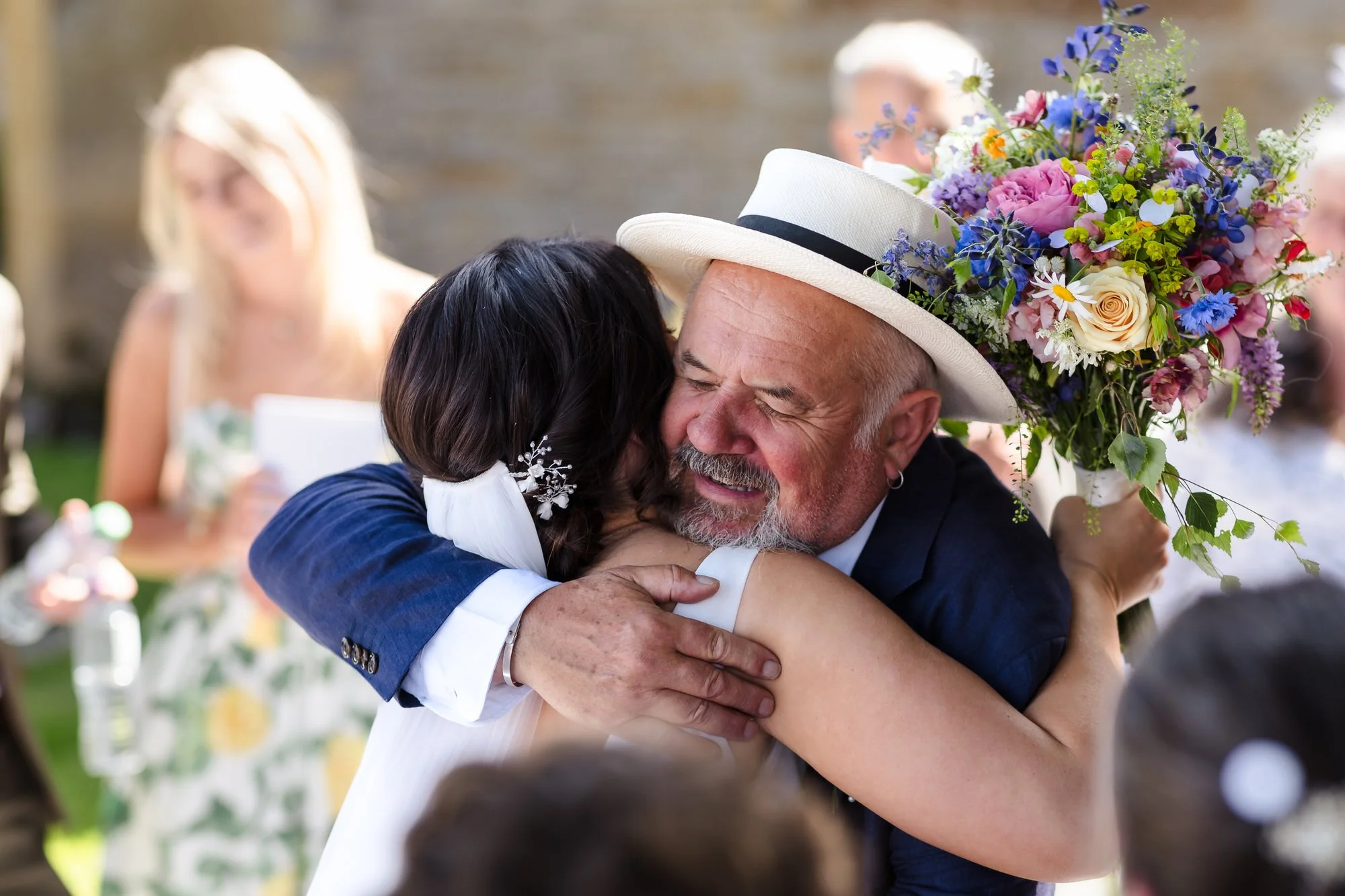 Bride embracing her father in a Panama hat outside St Leonard's Church, candid emotional moment at a Worcestershire wedding