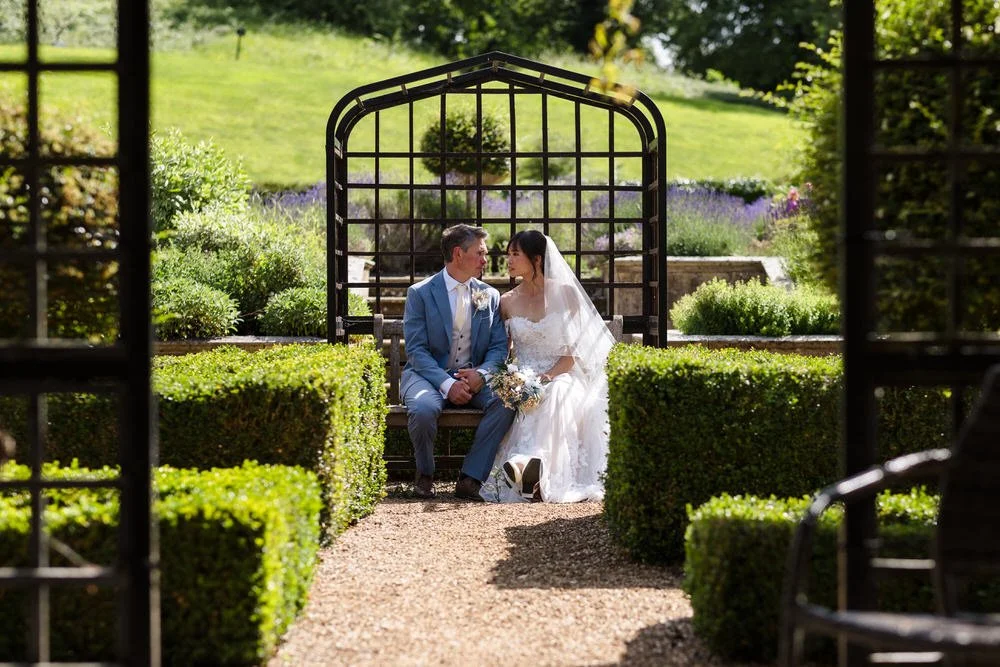 Christine and Greg seated beneath a pergola in the Italian Garden's box hedges at The Welcombe Hotel, Warwickshire.