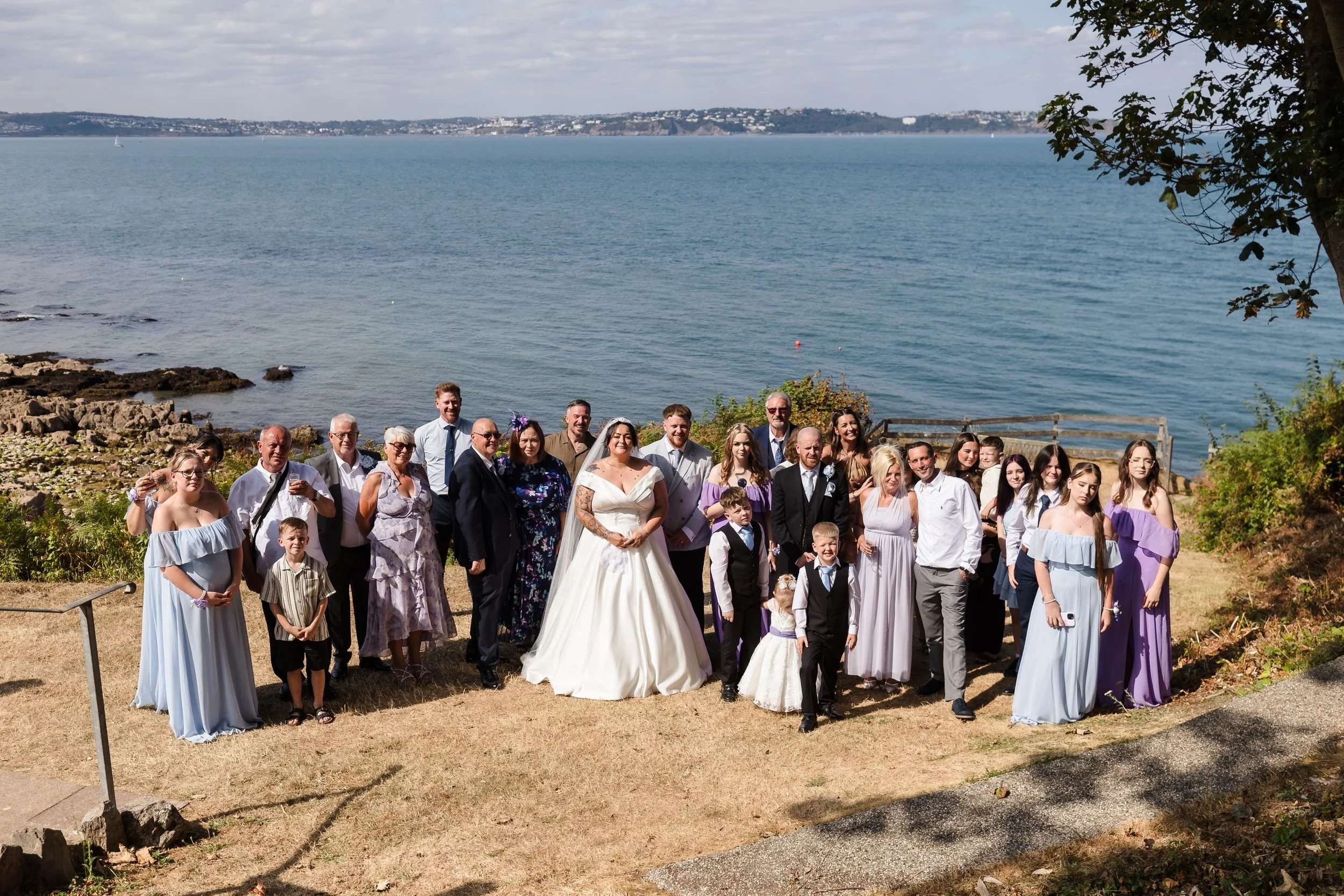 Wedding guests on the front lawn of Berry Head Hotel with the bay behind them