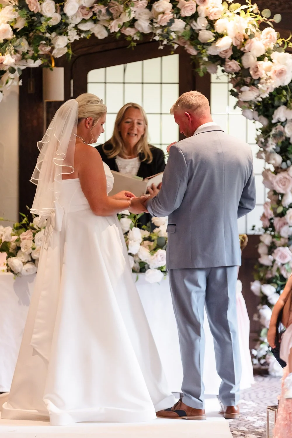 Jess and Brian exchanging vows under floral arch at Hogarths Stone Manor Drawing Room ceremony, Worcestershire wedding photography