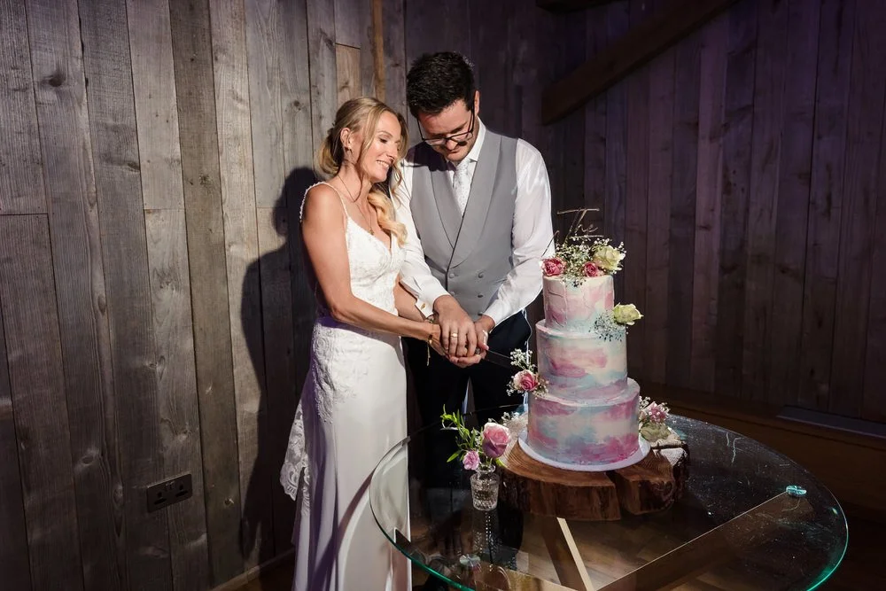 Cake cutting ceremony at Bredenbury Court Oak Barn wedding reception with watercolor cake design