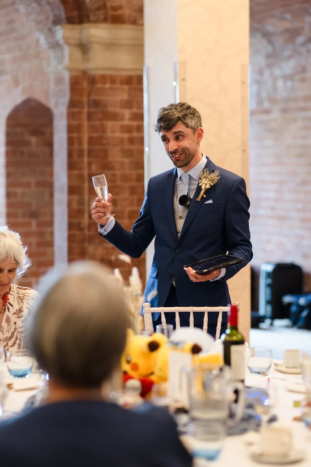 The best man raising a toast during speeches at The Welcombe Hotel, with a Pikachu detail visible on the table.