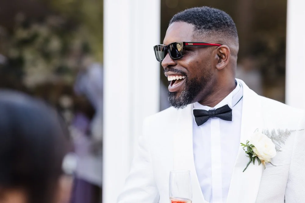 Groom in white dinner jacket, black bow tie and Gucci sunglasses laughing at Hogarths Hotel Solihull — wedding photography by Once in a Lifetime Photography, Worcestershire