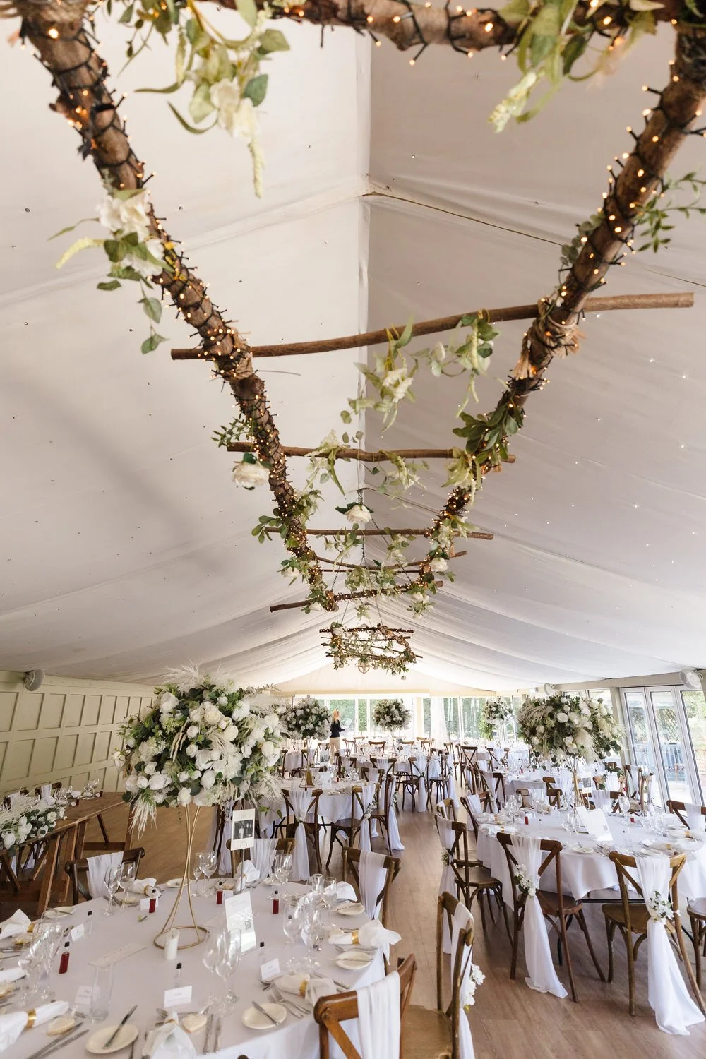 Elegant wedding reception setup with floral centrepieces and rustic ceiling decor at Hogarths Hotel wedding venue.