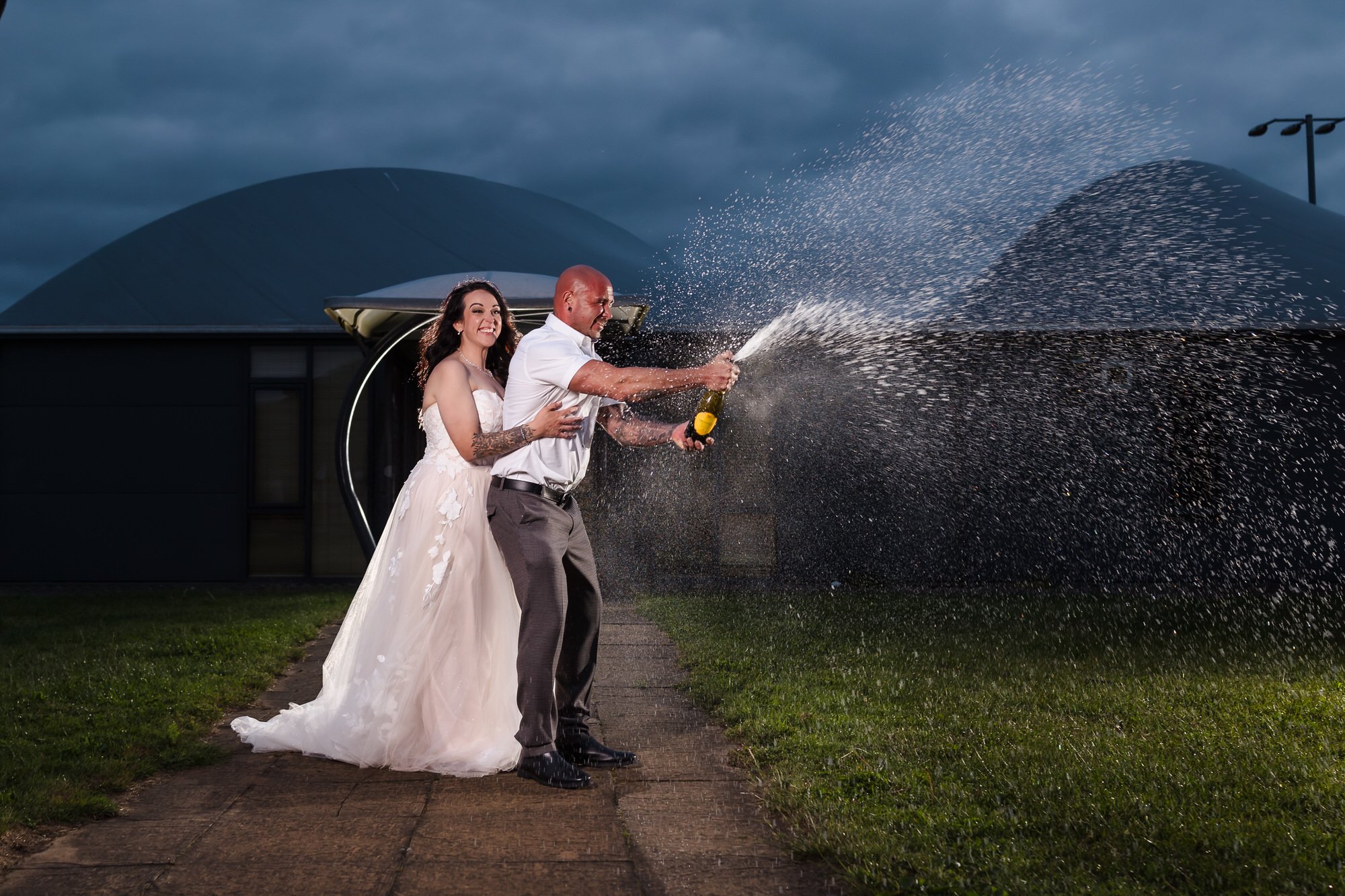 Champagne spray portrait at dusk, creative wedding photography at Stourport Sports Club, Worcestershire.