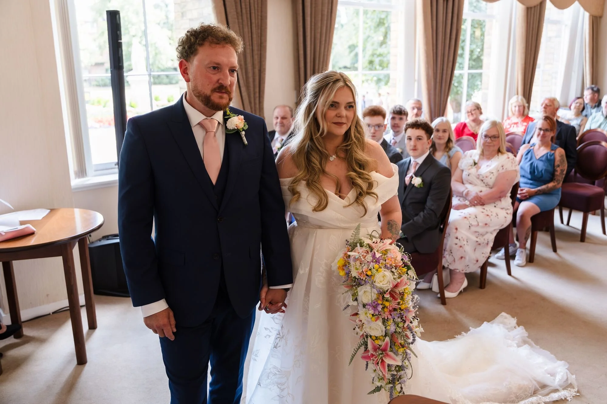 The couple standing together in the chandelier-lit ceremony room at Lichfield Registry Office, wedding photography by Once in a Lifetime Photography.