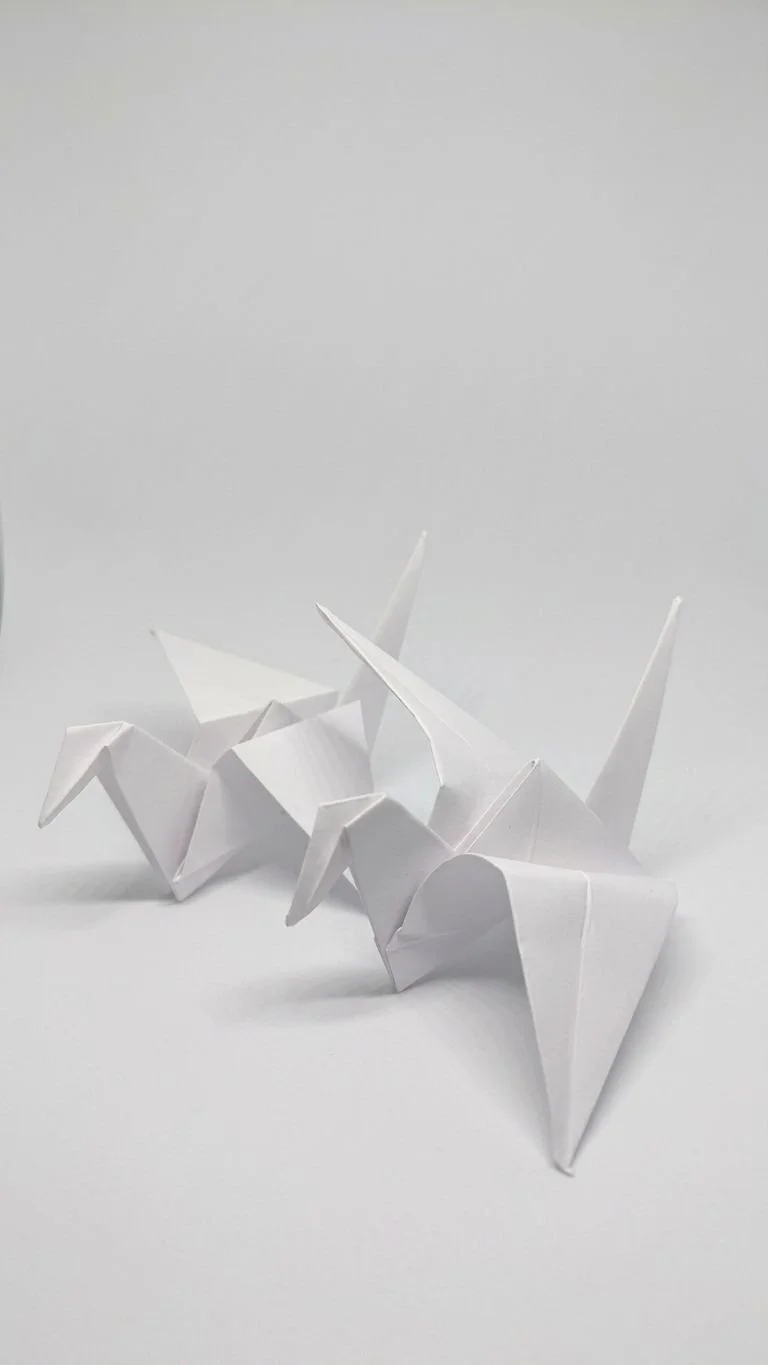 White paper origami unicorn on a white surface with a plain white background.