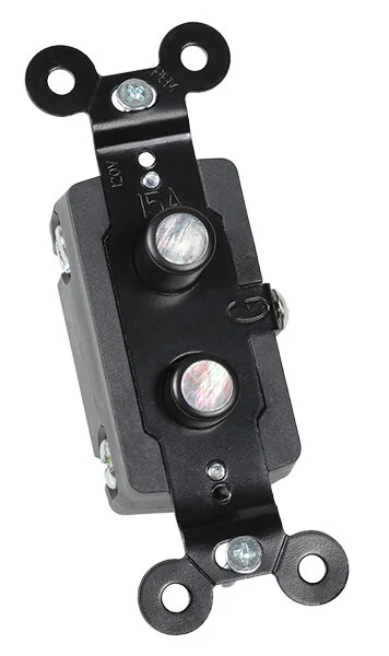 A push-button light switch with mother-of-pearl inlay. Seen in three quarter view.