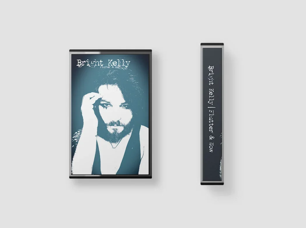 A cassette album shown from front and side view.The framed image shows a portrait of a man with long hair and a beard, touching his temple with his right hand. Text on the display reads "Bright Kelly" and "Flutter & Wow".