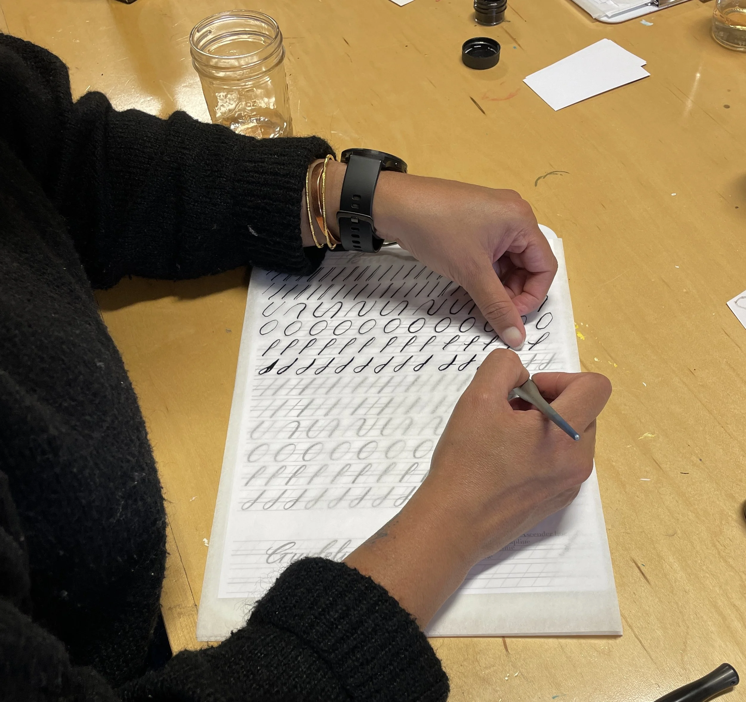 a person practices basic calligraphy strokes using tracing paper and guidelines