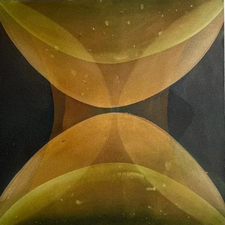 Close-up of a reflective, metallic surface with a symmetrical pattern of overlapping yellow and brown curved shapes.