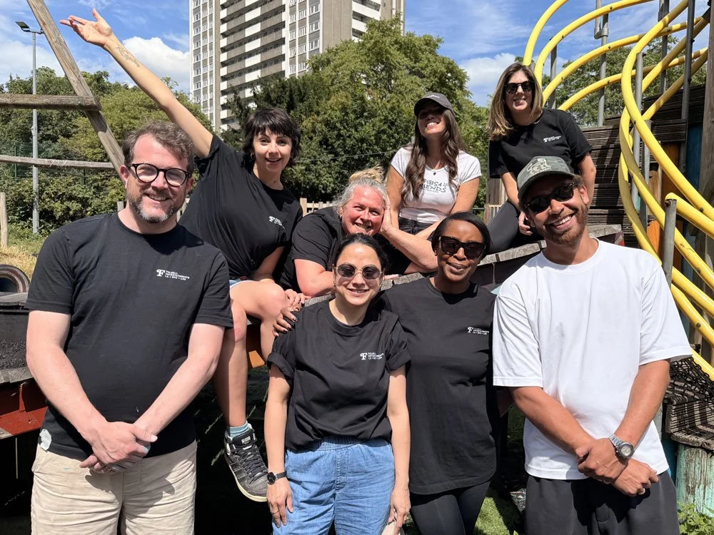 A group of smiling people standing around a play structure