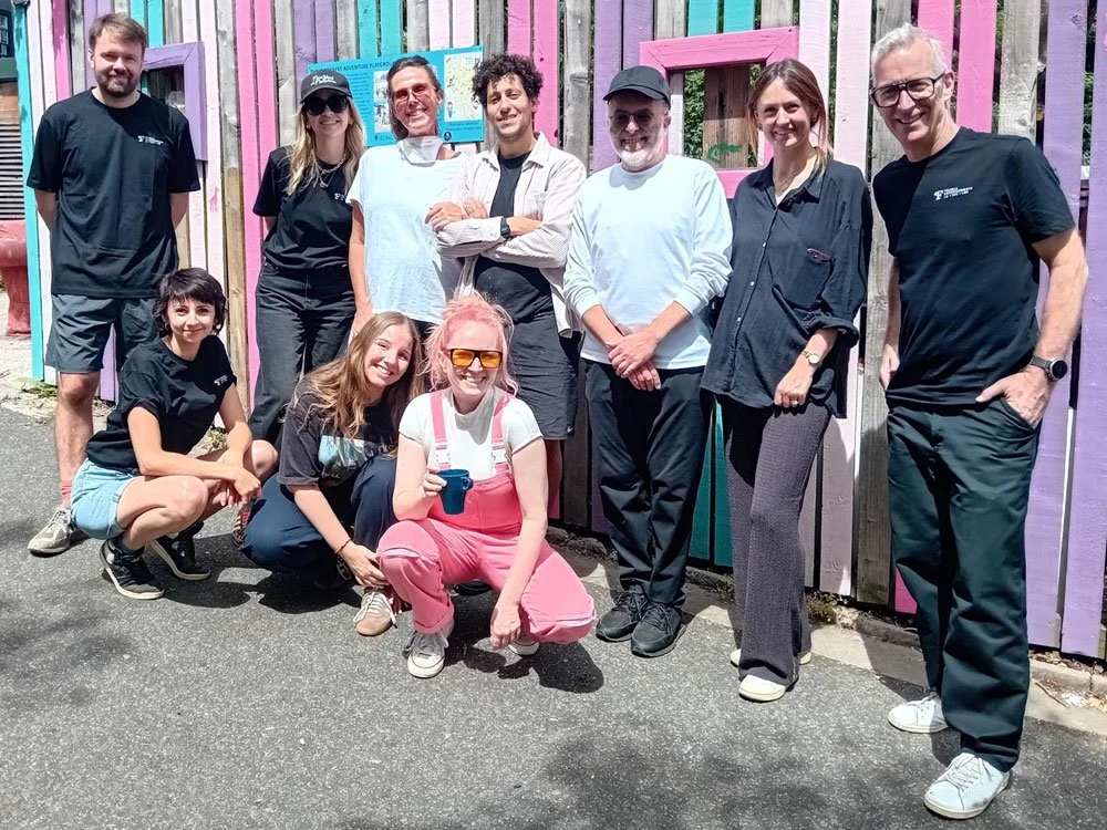 A group of smiling volunteers in front of a colourful fence