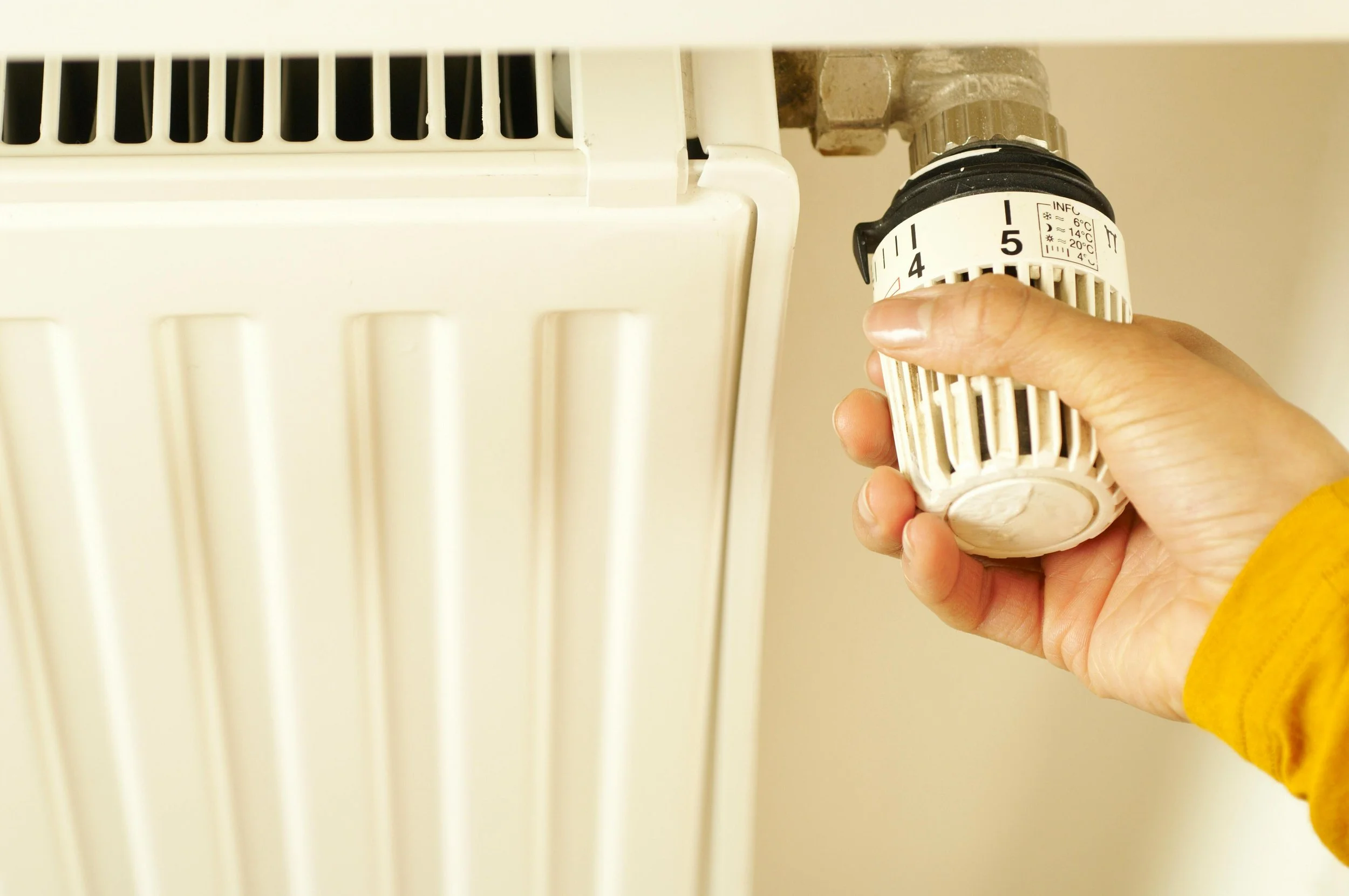 Person turning down the temp on radiator