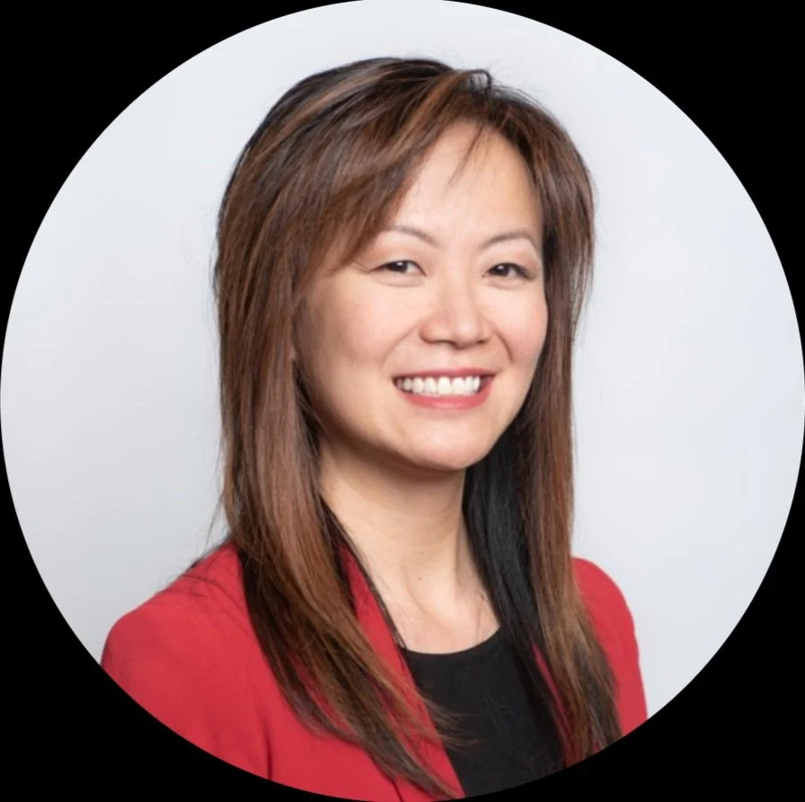 Professional woman with long brown hair wearing a red blazer and black top, smiling against a white background.