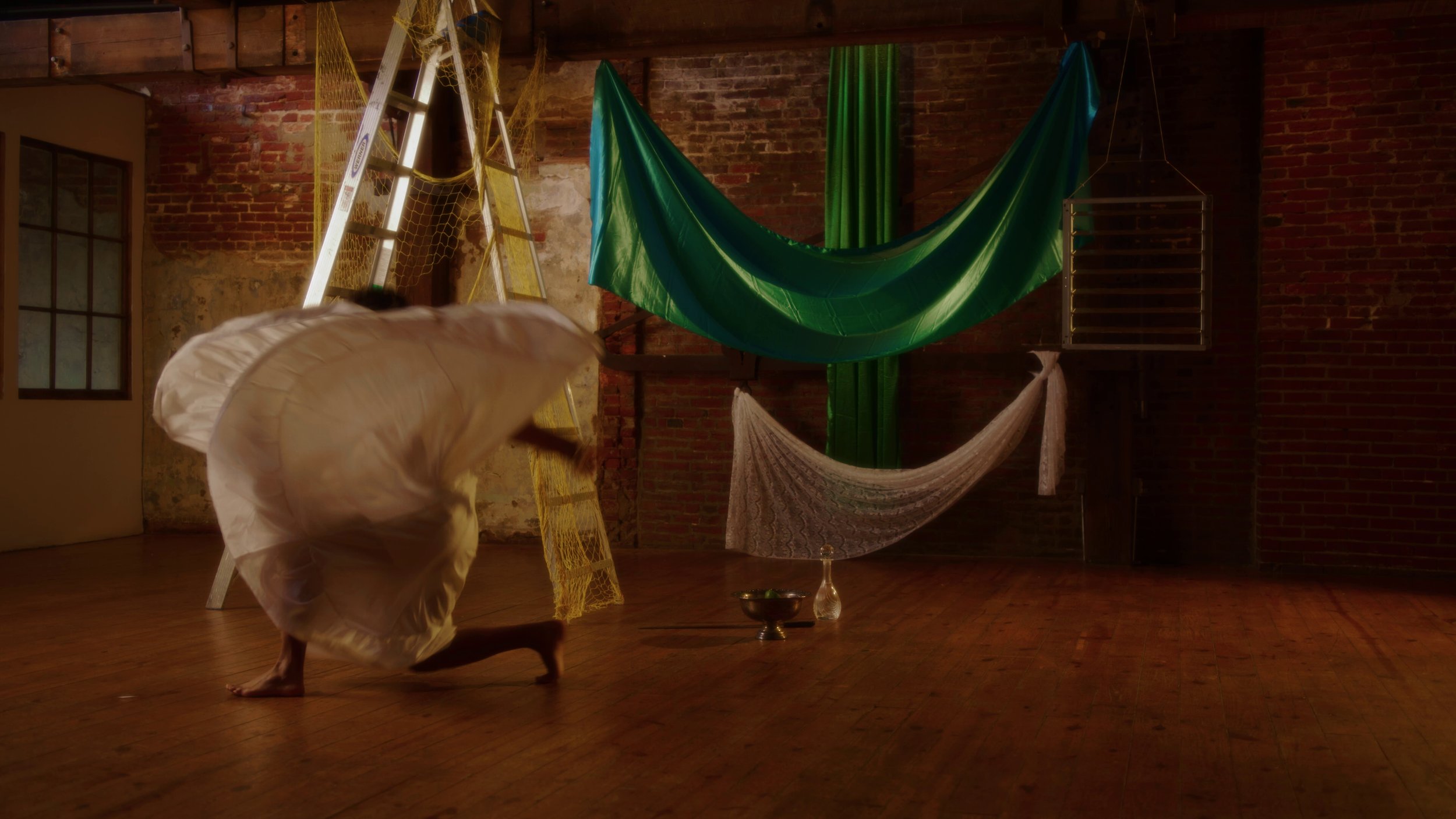 film still in a room with a brick wall and a dancer in motion