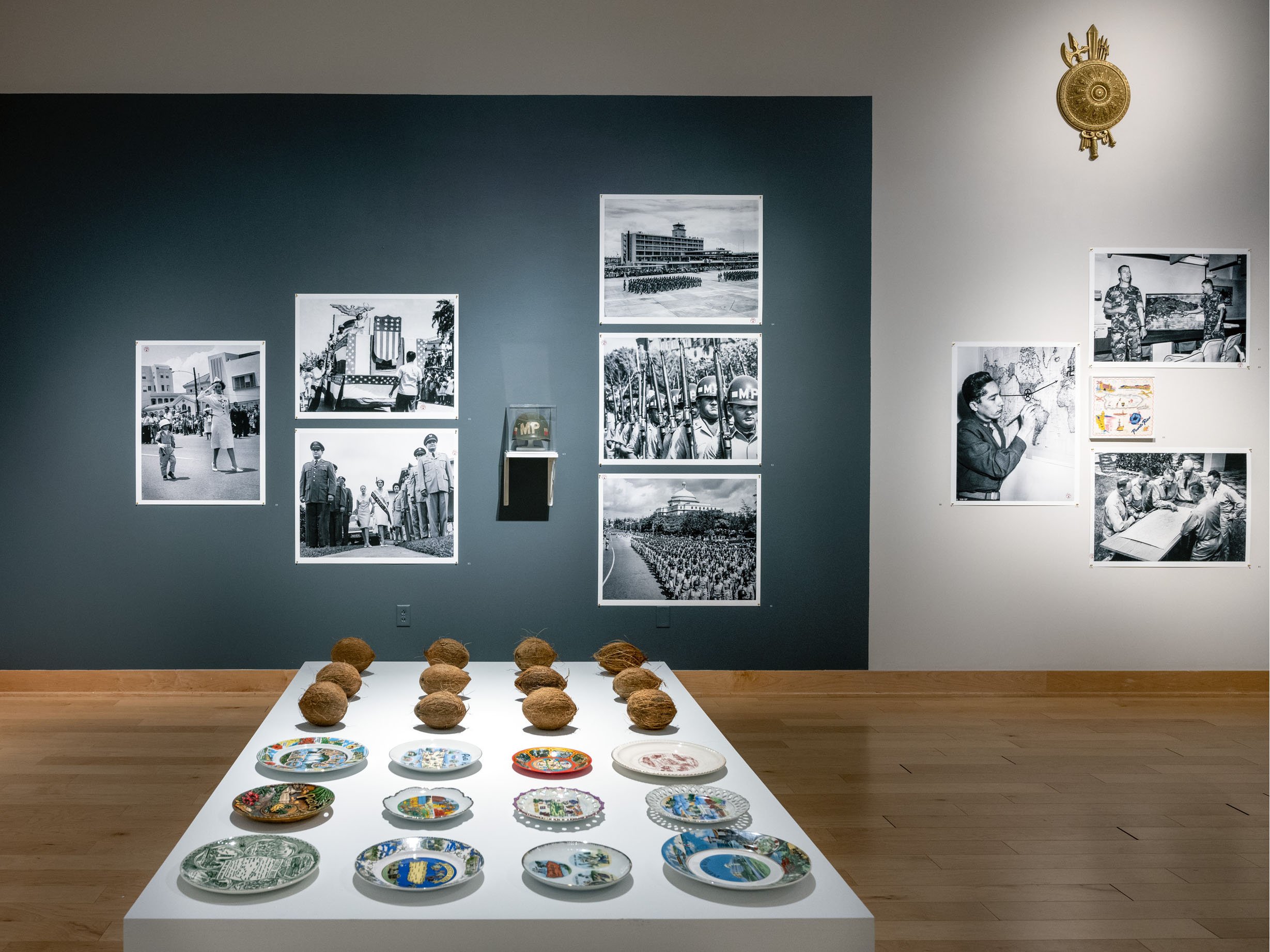  Installation view.  Platos y Cocos  (foreground) and military related photographs and objects from 1939-1988 | 2019-2022.  The Museum of the Old Colony , Duke Hall Gallery of Fine Art, 2022. 