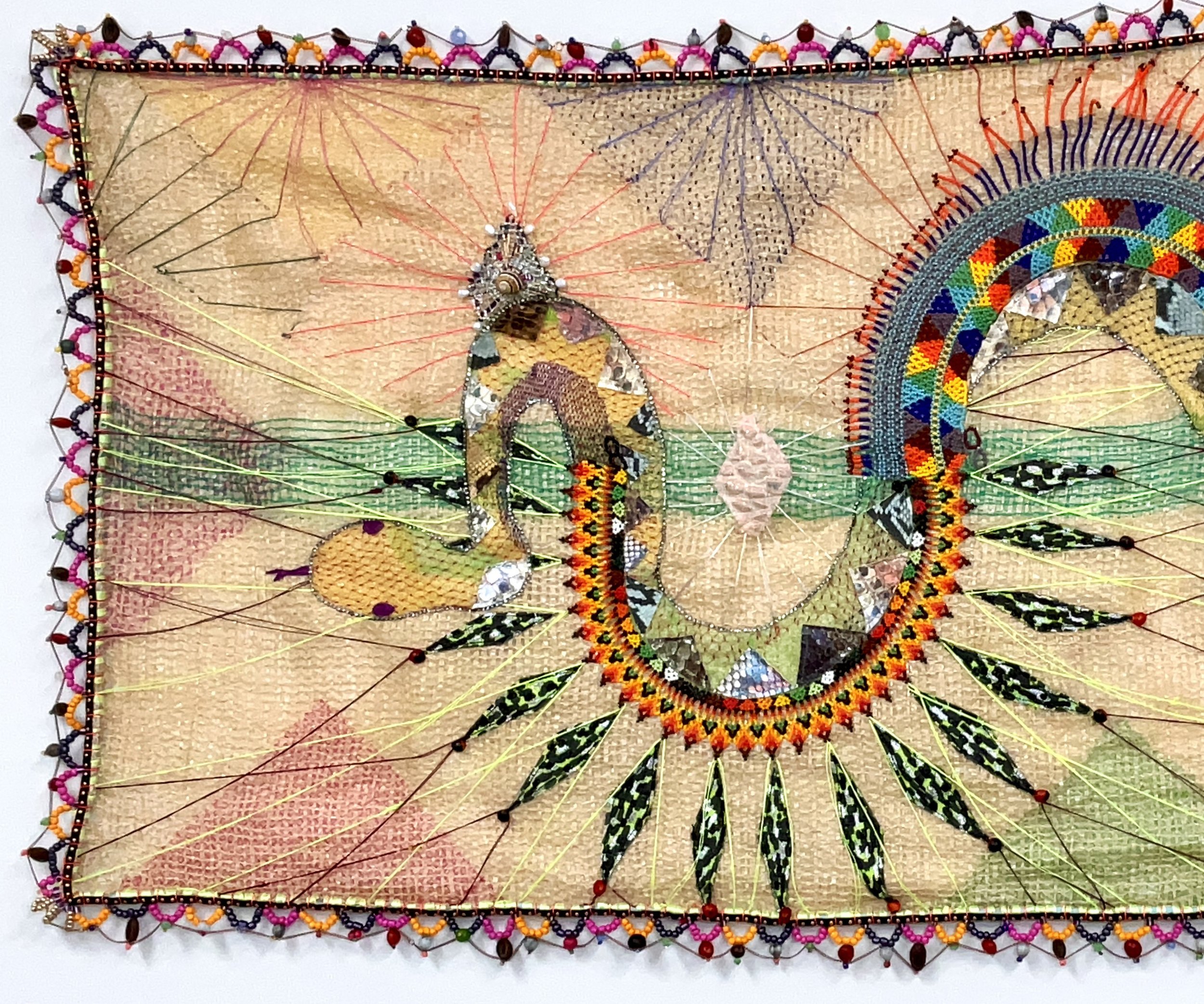 a tapestry with a beaded edge and a beaded snake in the middle