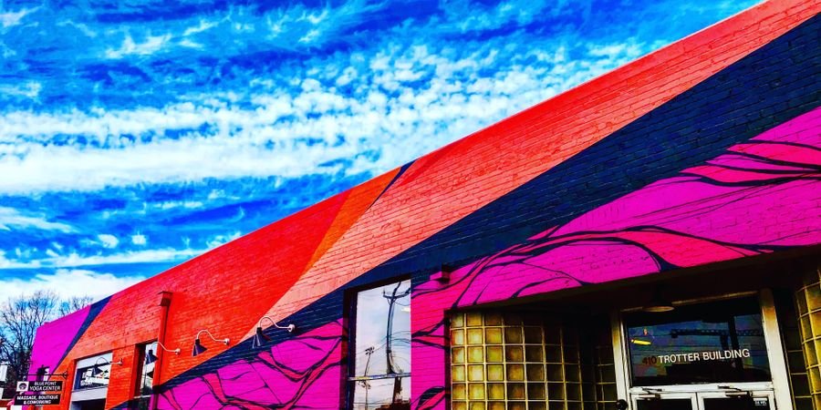 image of Living arts collective building in durham with bright pink and red diagonal stripes across a  low brick building