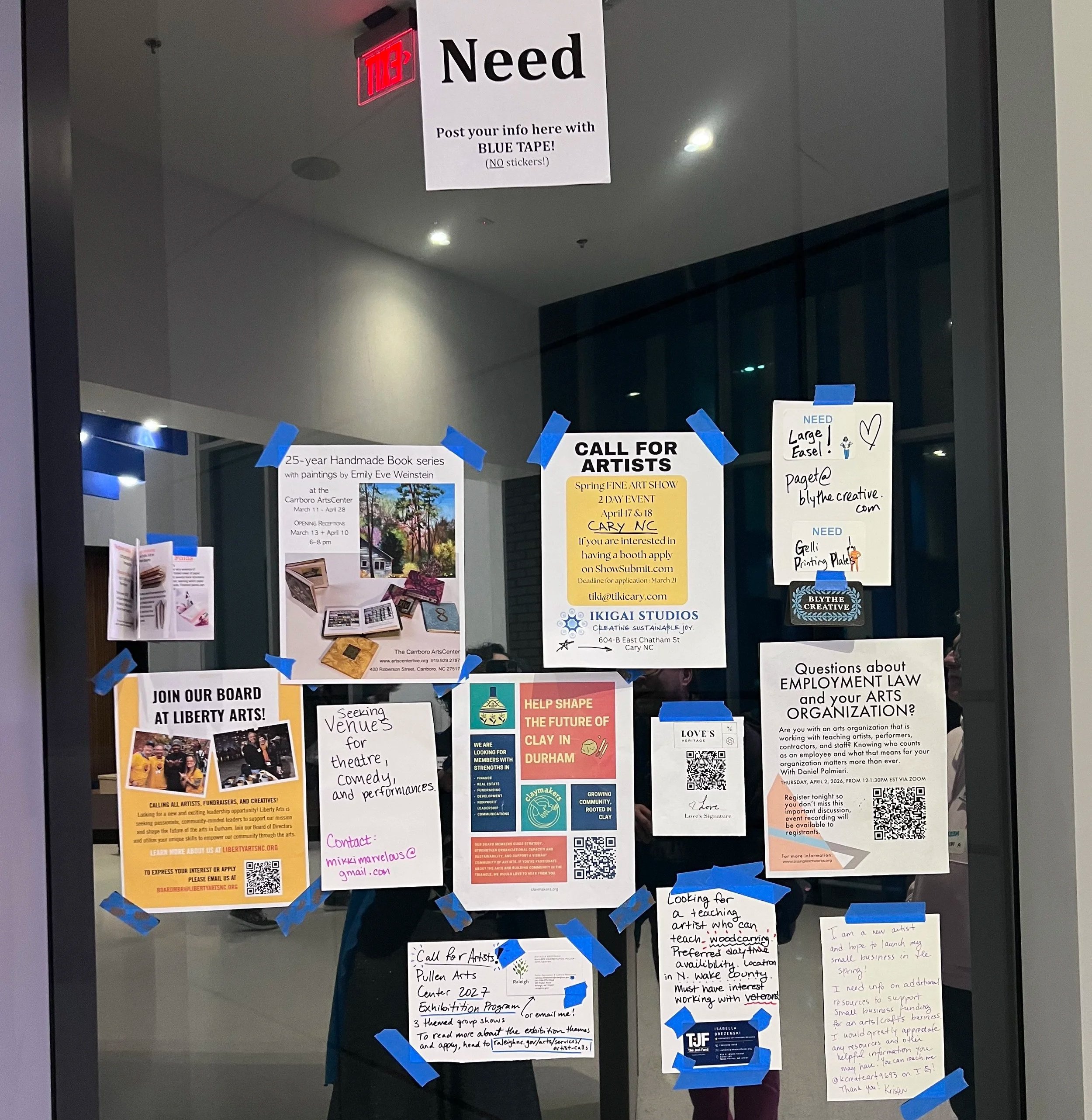 An image of a glass wall with many pieces of paper, printed with requests or offers for studio space, support, jobs, gigs, work and grants for artists and performers taken at SMASH! 2026 in North Carolina
