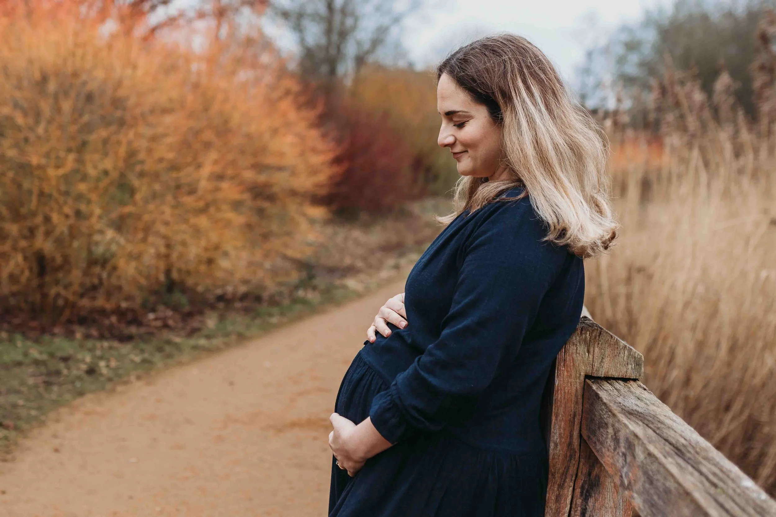 Pregnant mum holding bump in Richmond park
