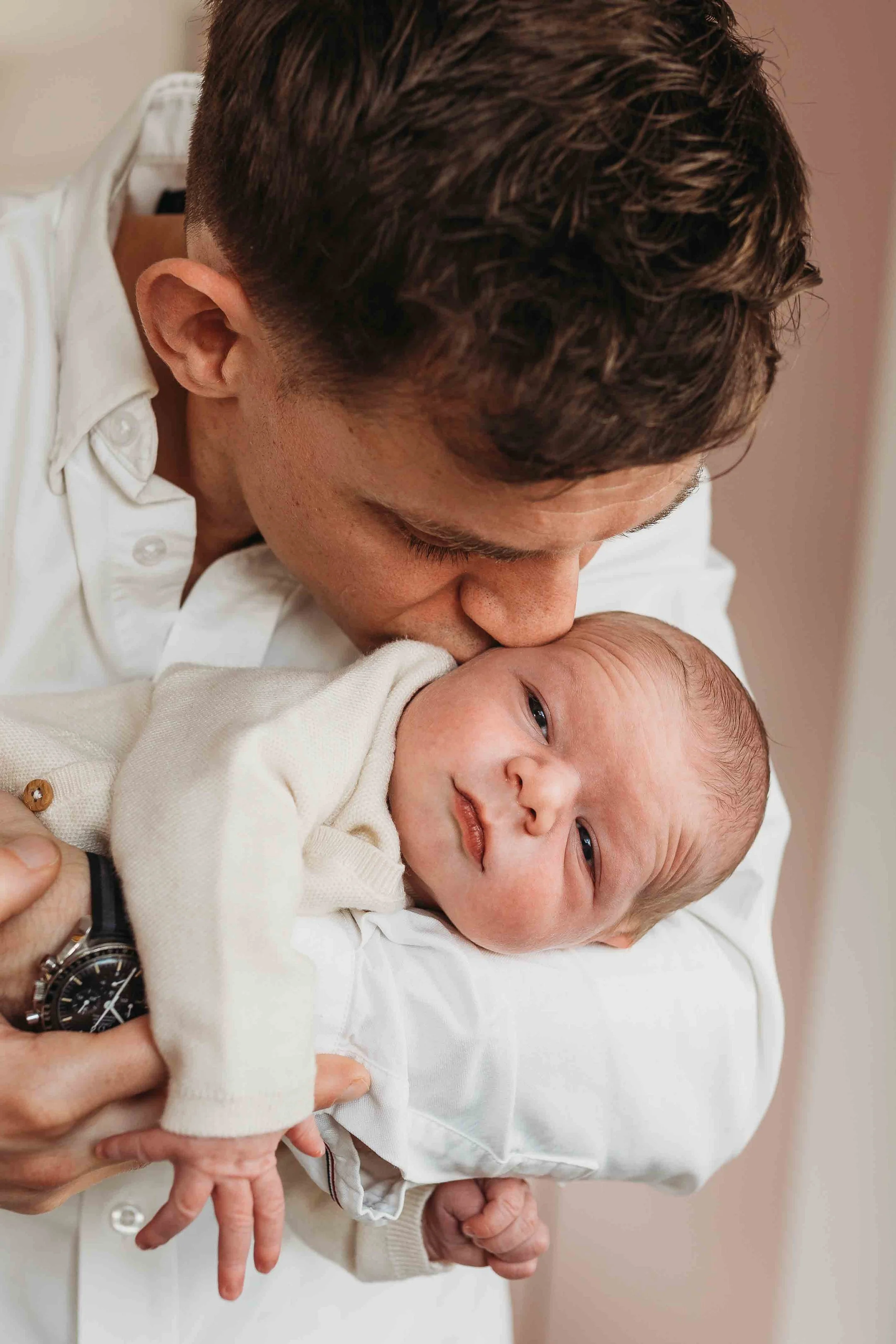 father kissing newborn baby on the cheek during an at-home newborn photoshoot in London