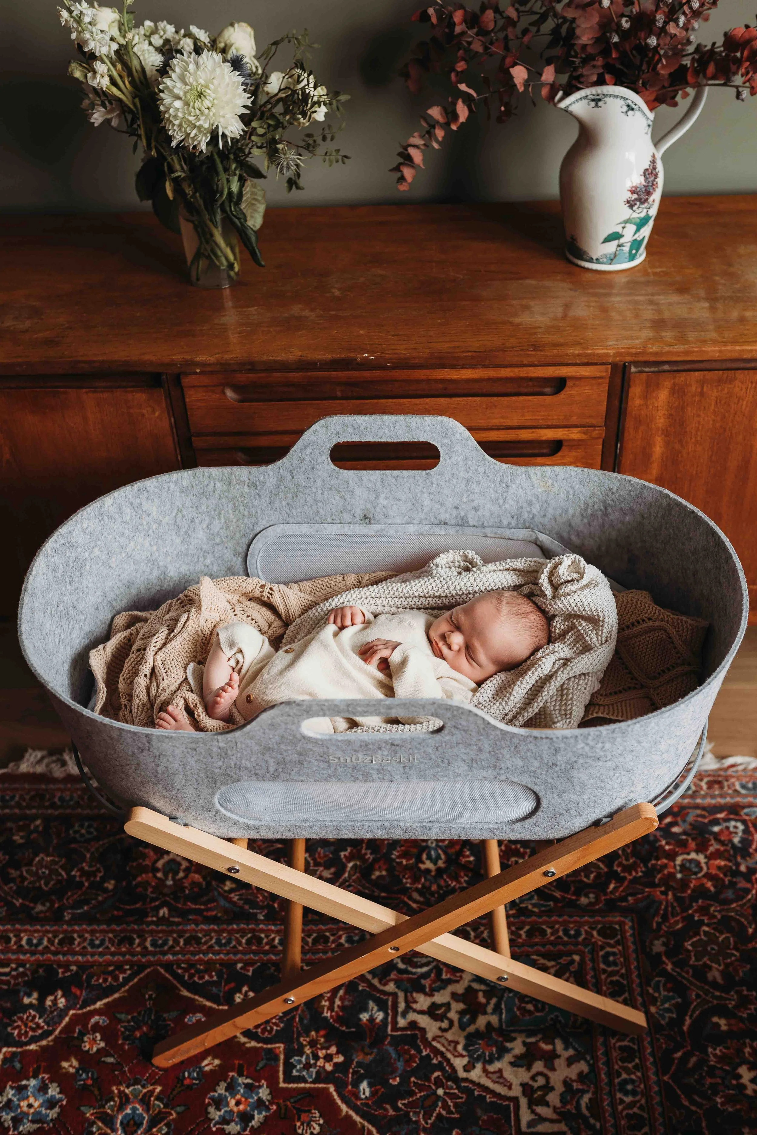 newborn baby sleeping in a felt bassinet with cosy blankets during an at-home newborn photography session
