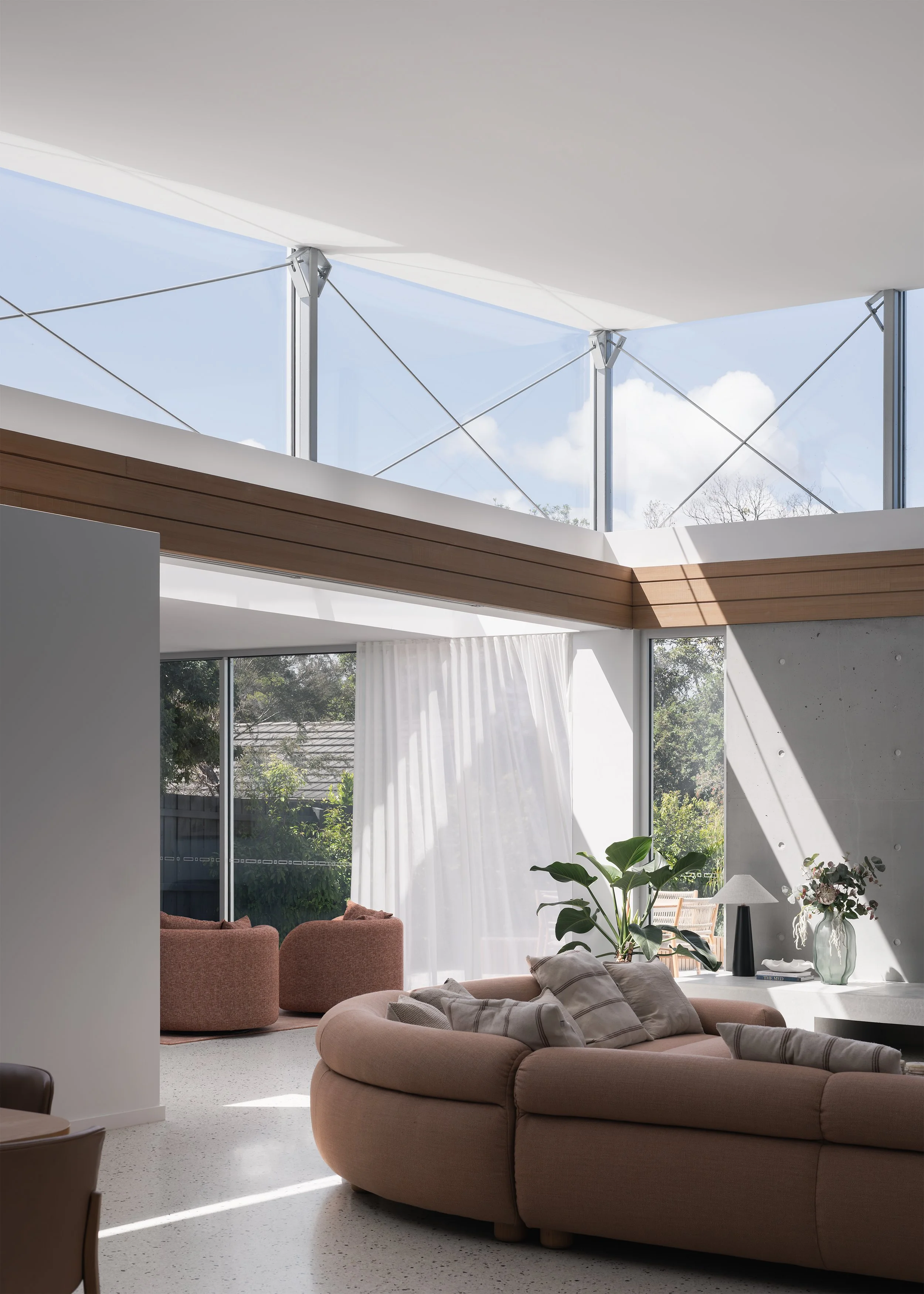 Light-filled modern living space beneath high-level glazing, with timber detailing and exposed concrete at this contemporary Mornington home.
