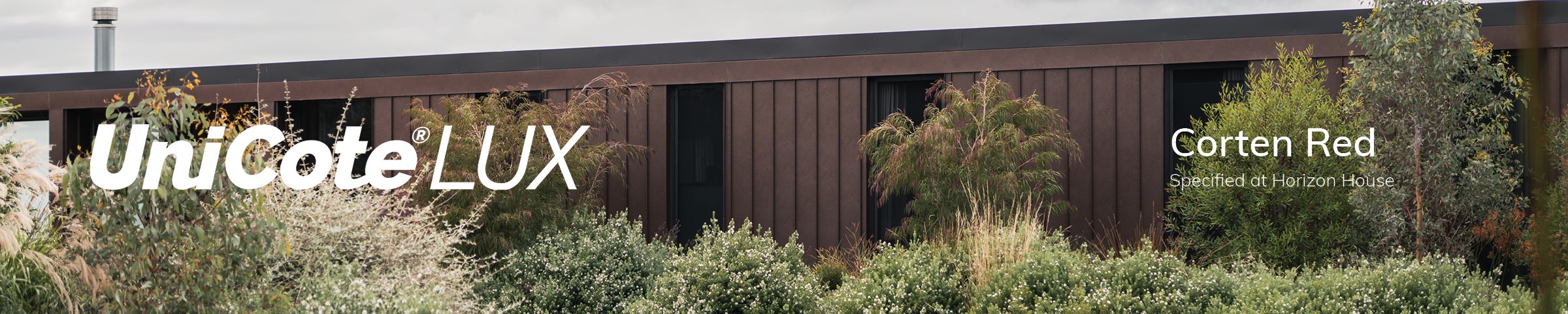Wide view of Horizon House by Neil Architecture, with UniCote LUX Corten Red cladding framed by established native planting.