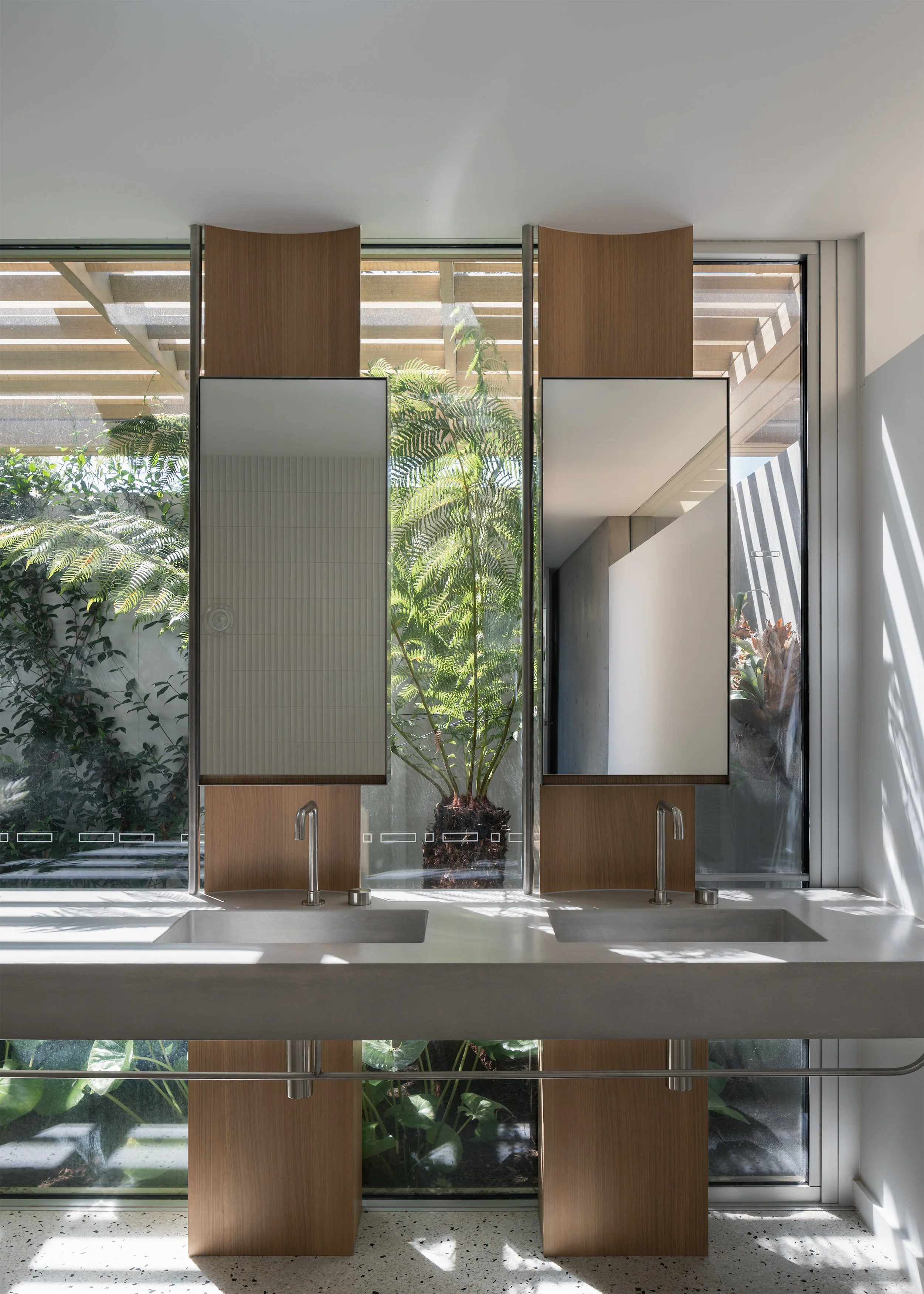 Double vanity and mirrored bathroom joinery overlooking lush garden planting in Channel by Megowan Architectural.