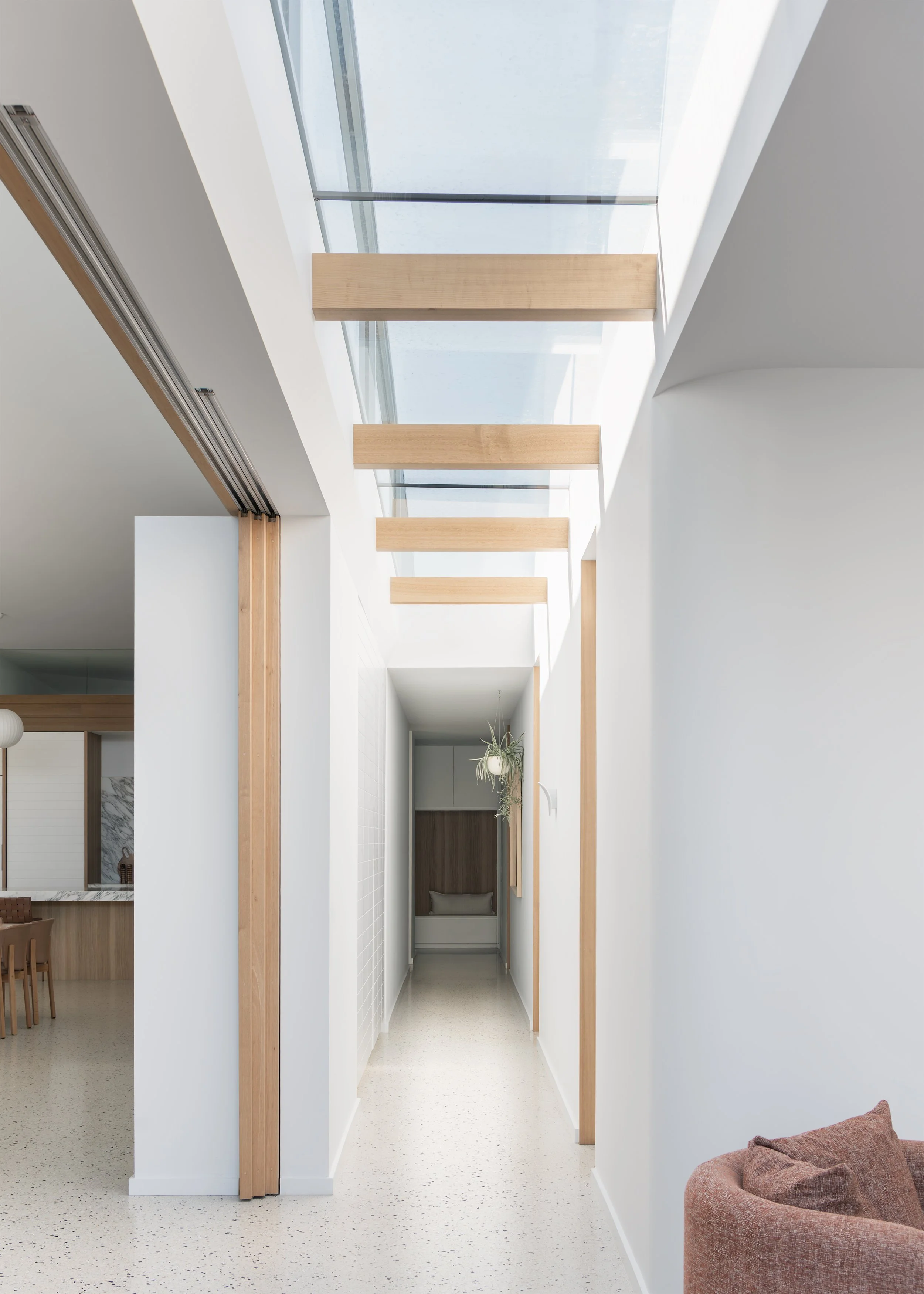 Skylit hallway with timber beams and polished concrete flooring in this contemporary Australian house in Mornington.
