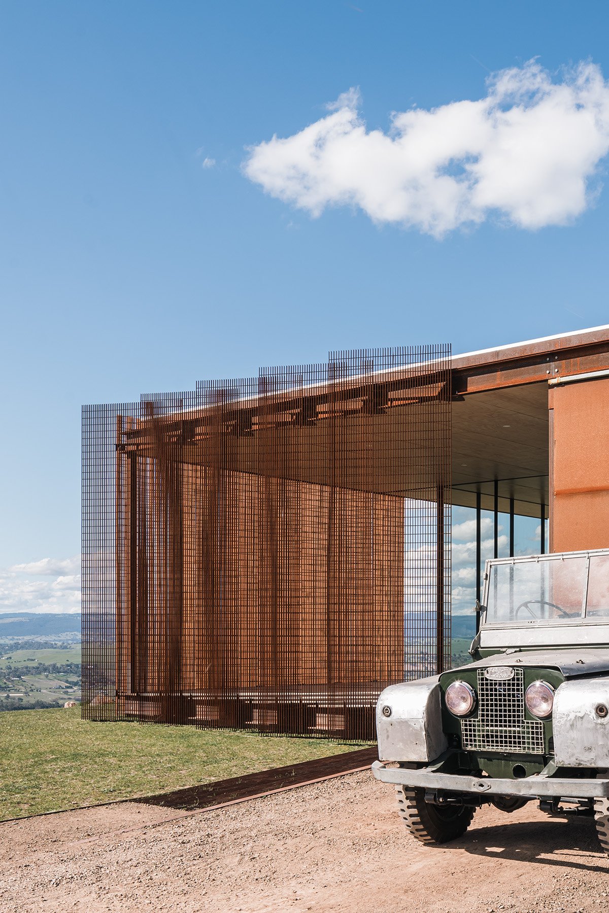 Weathered-steel screen facade and vintage four-wheel drive at Mansfield House, an off-grid home in regional Victoria.