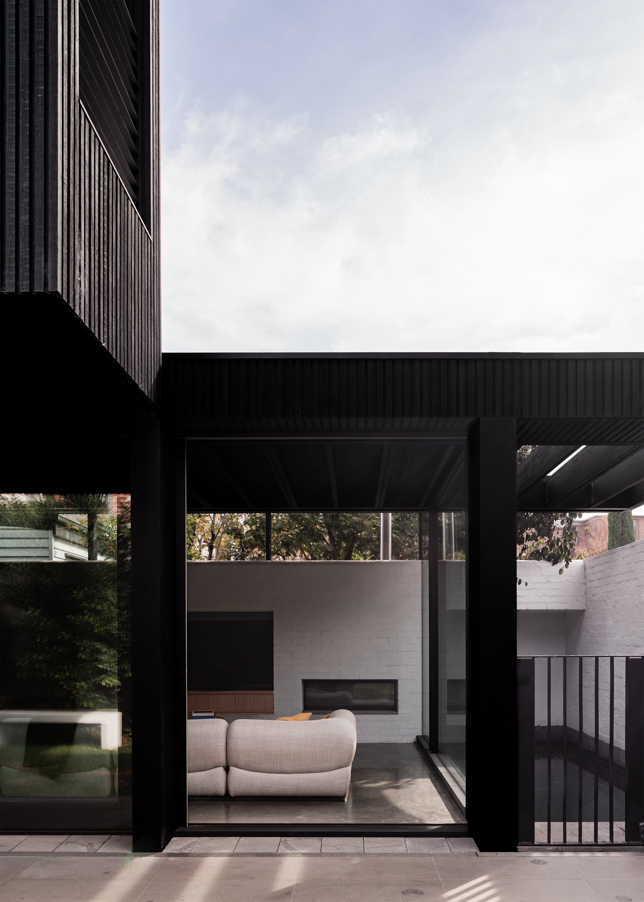 Glazed garden elevation revealing the living room behind the black timber structural frame.