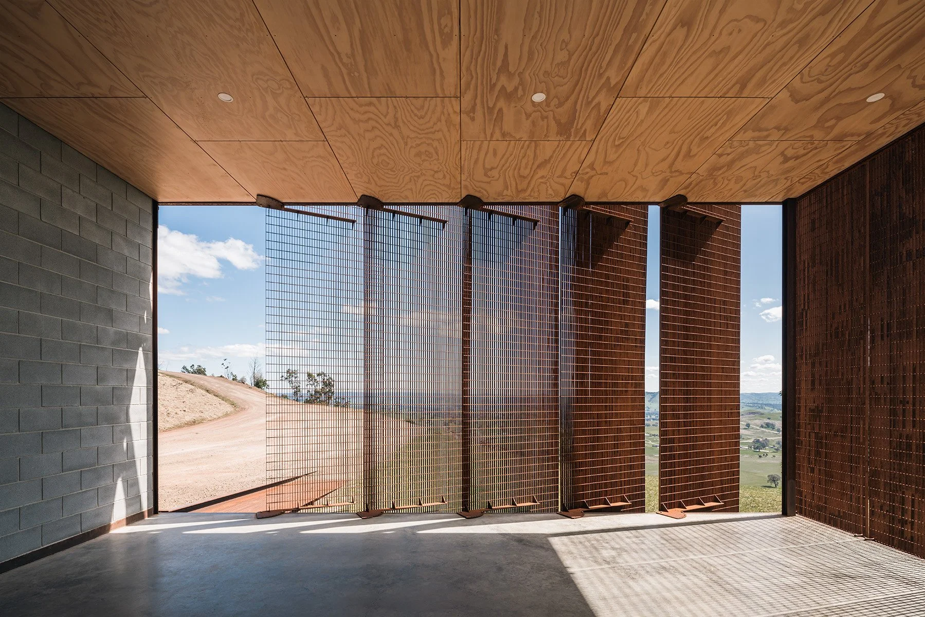Pivoting weathered-steel solar screens filter western light while preserving views from the off-grid Mansfield House.