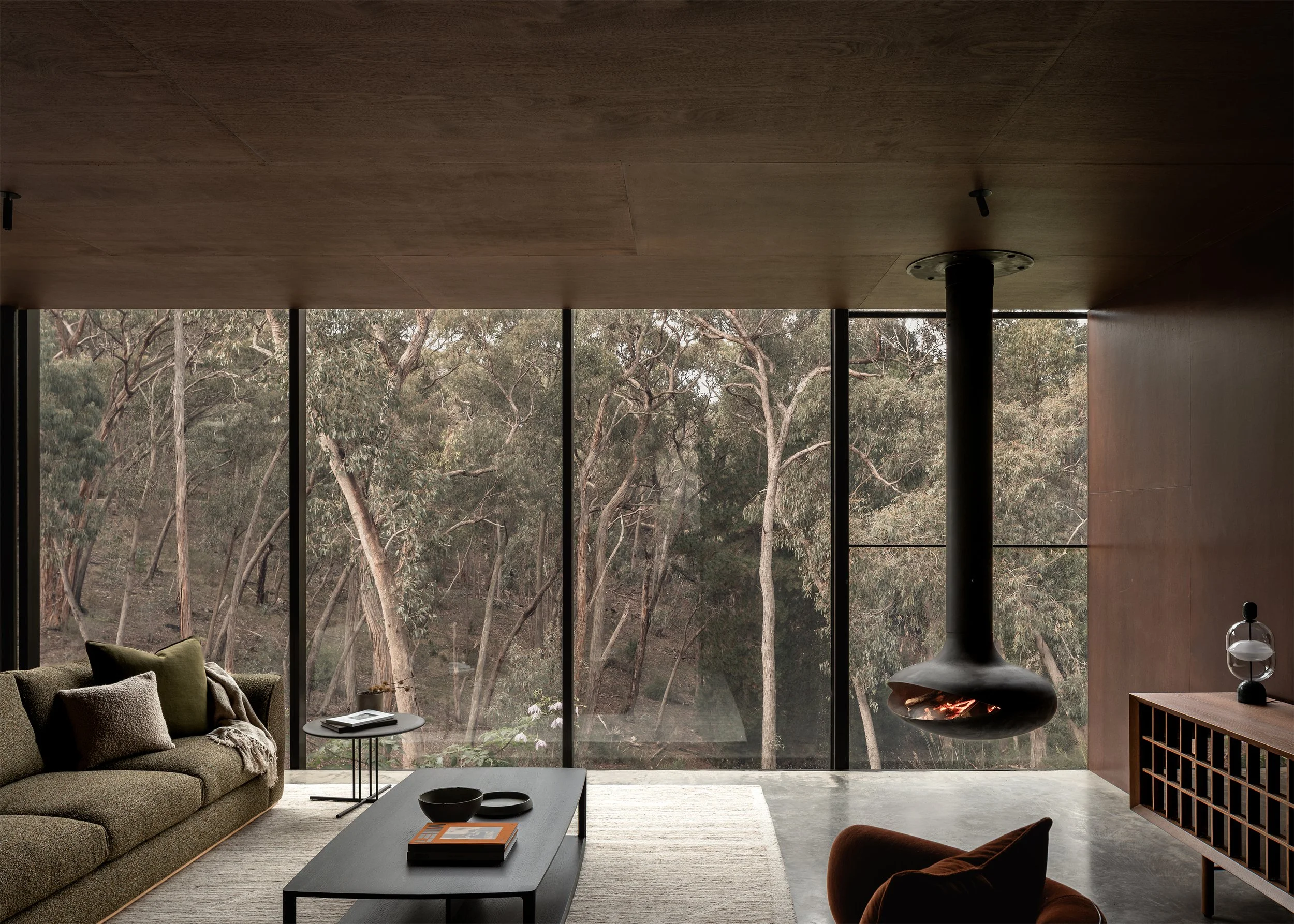 Open living room with Cosh Living furniture facing a wall of glazing that frames the surrounding eucalypt woodland at Matchbox.