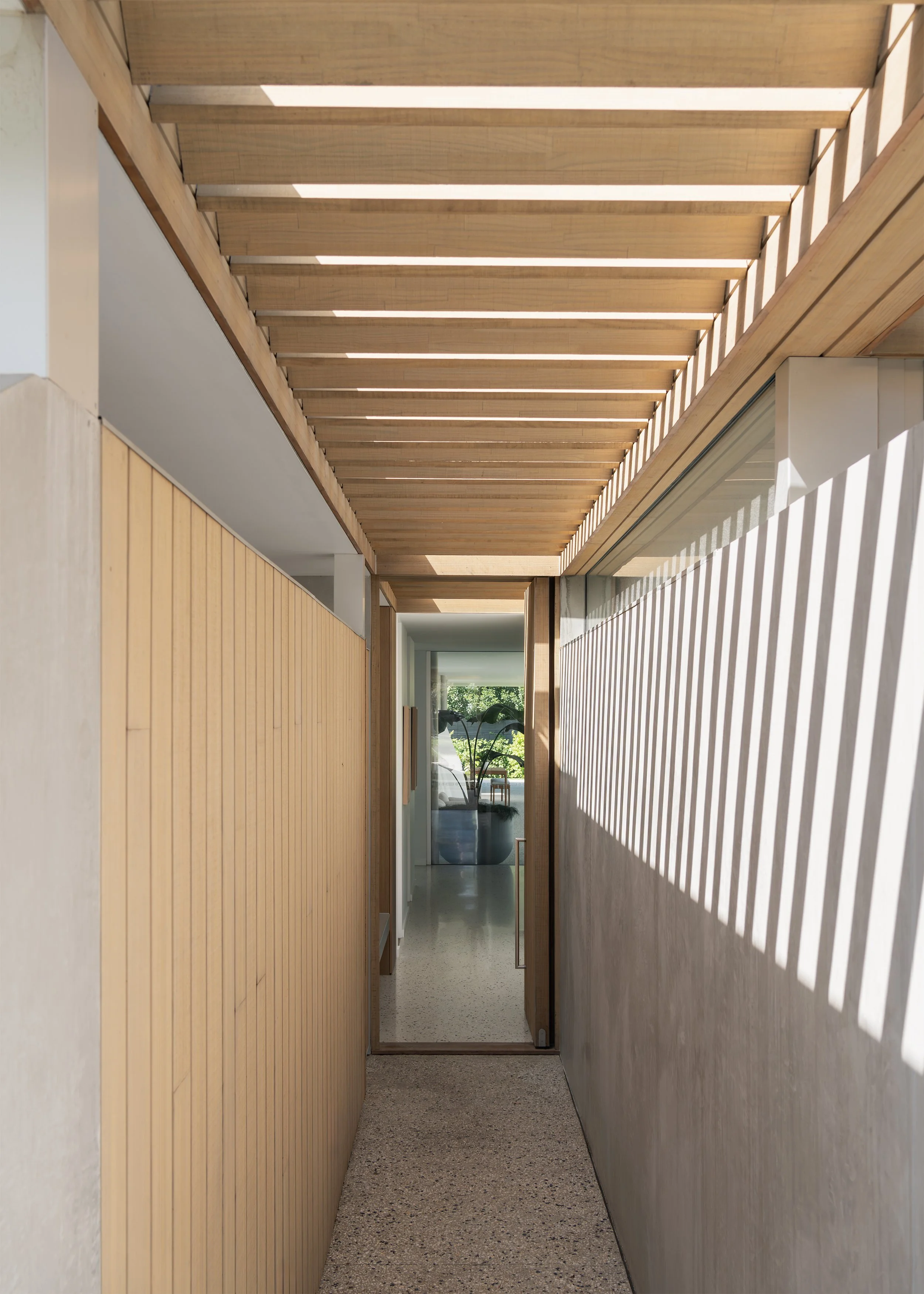 Timber-lined entry passage with filtered sunlight and exposed concrete walls at Channel in Mornington.