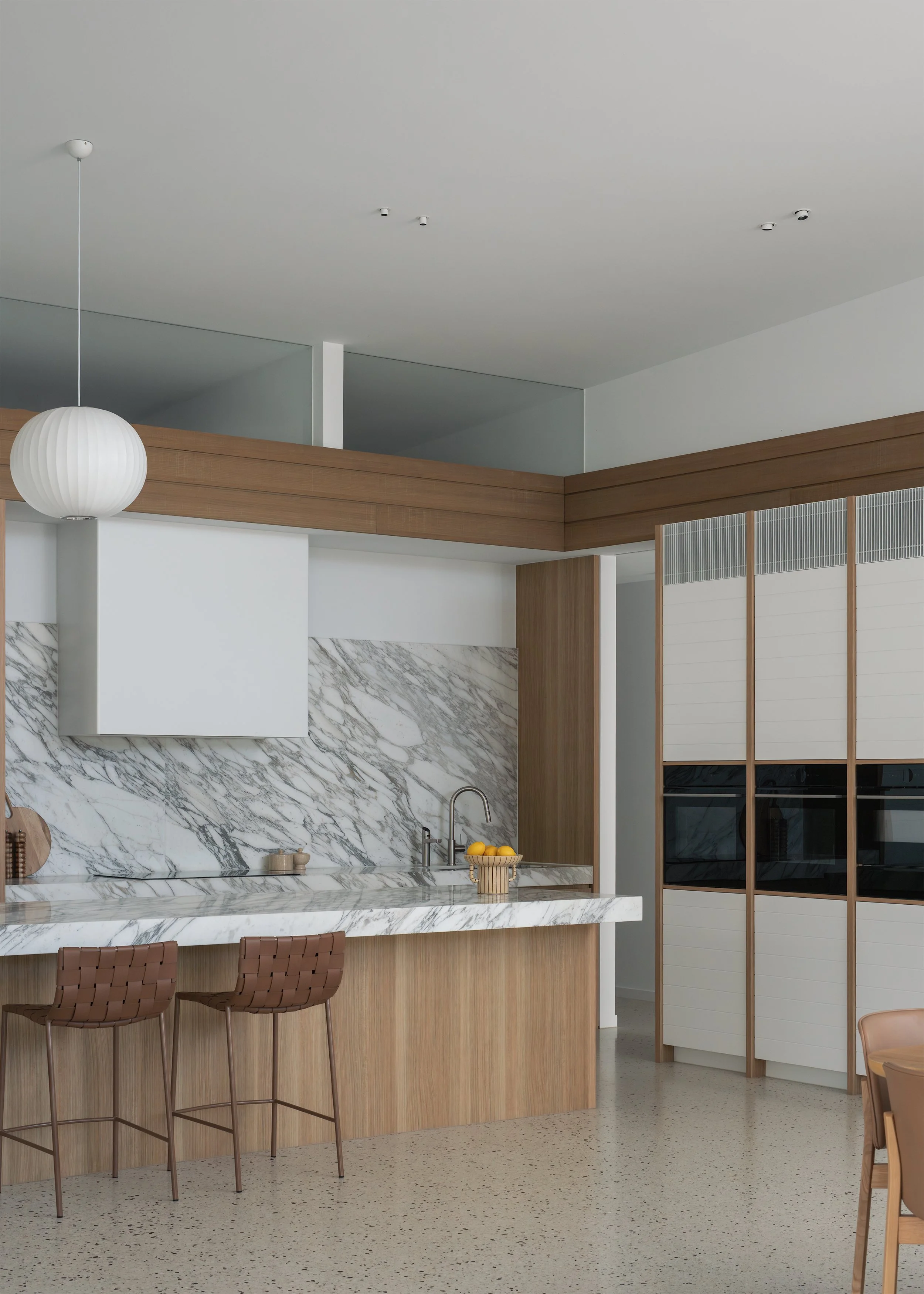 Timber kitchen with marble island and high-level glazing at Channel by Melbourne architecture practice Megowan Architectural.