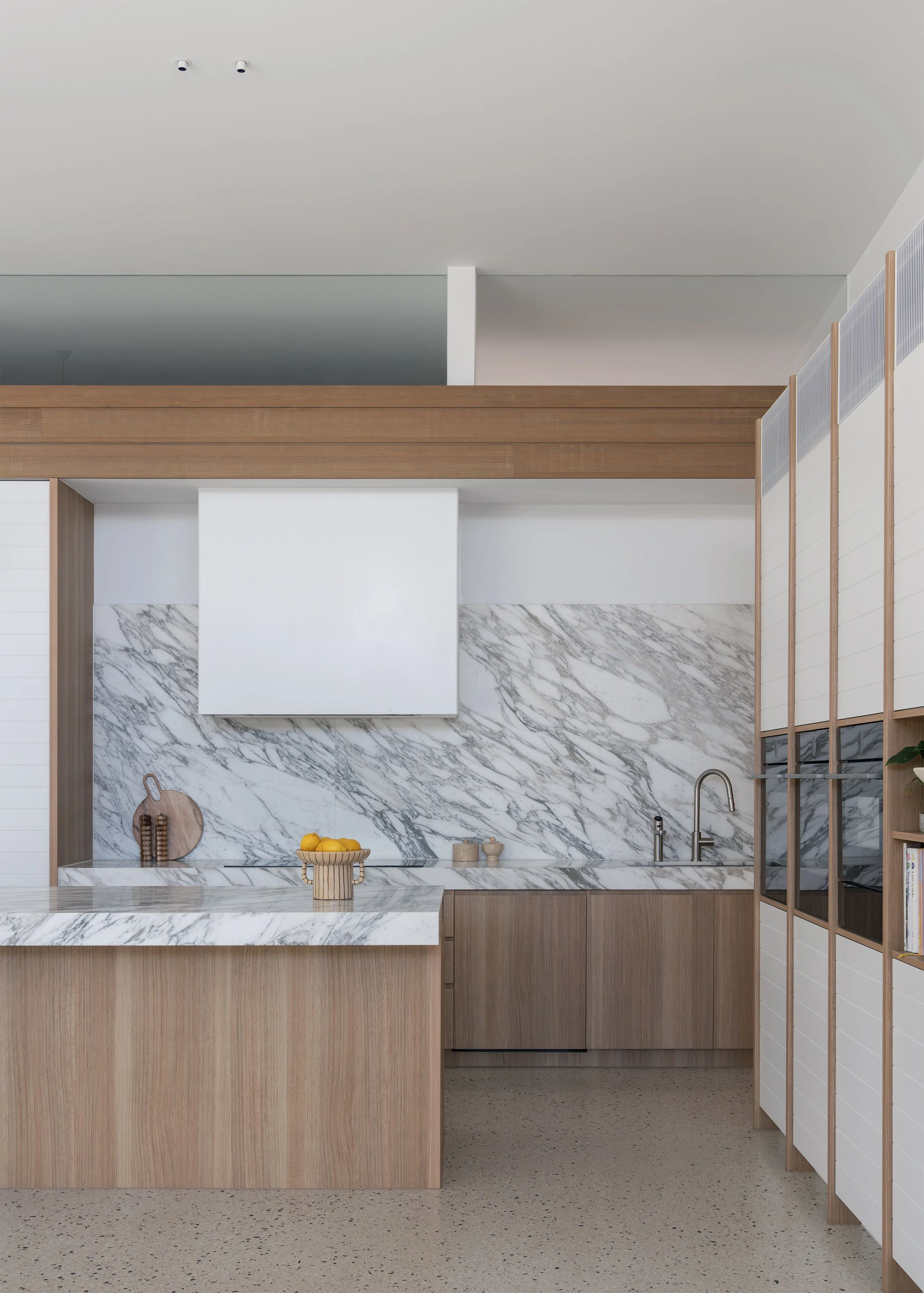 Timber and marble kitchen with restrained detailing in Channel, a contemporary new build by Megowan Architectural in Mornington.