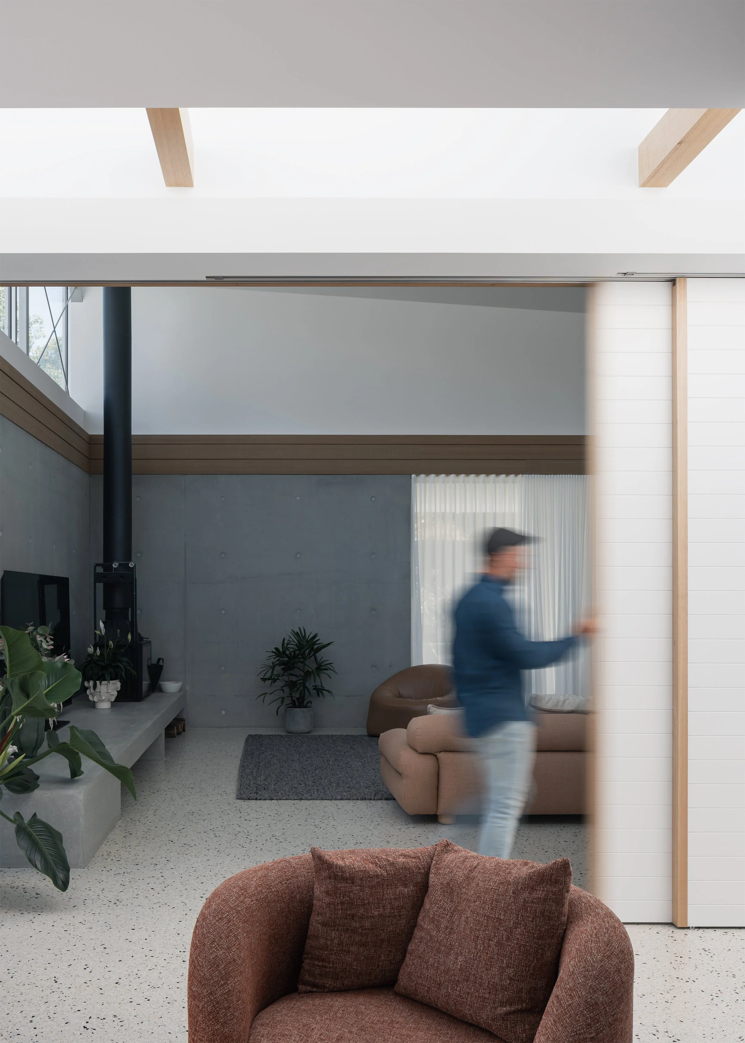 Flexible living areas connected by sliding walls beneath the elevated roof structure of Channel by Megowan Architectural.
