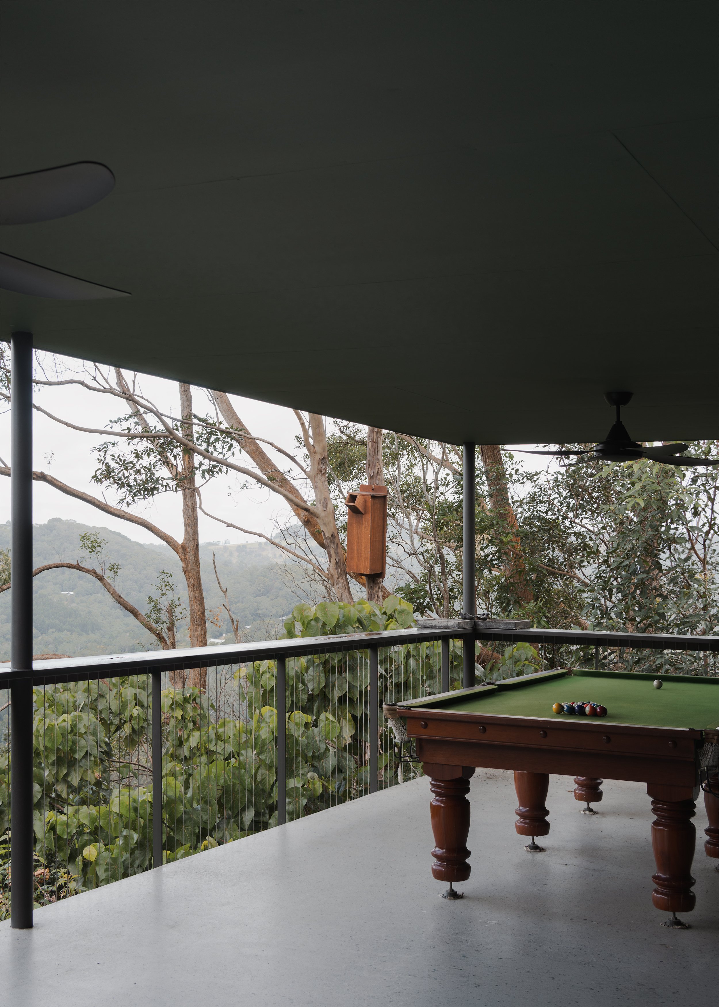 Pool table on the covered deck of Tallowwood Cabin, suspended among eucalypts with views across the Gold Coast hinterland.