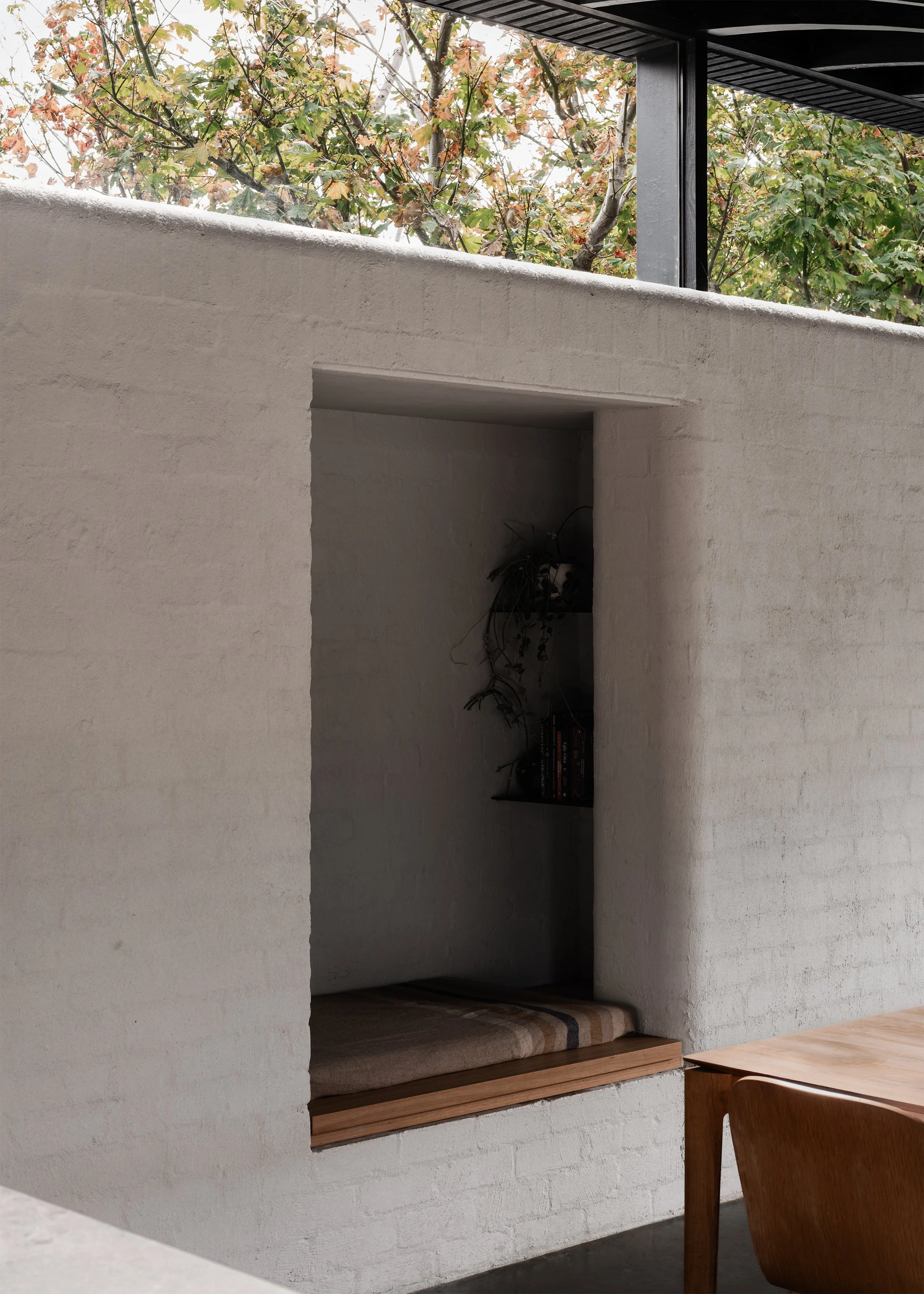 Built-in reading nook seat within the masonry wall, with neighbouring tree canopy visible above.
