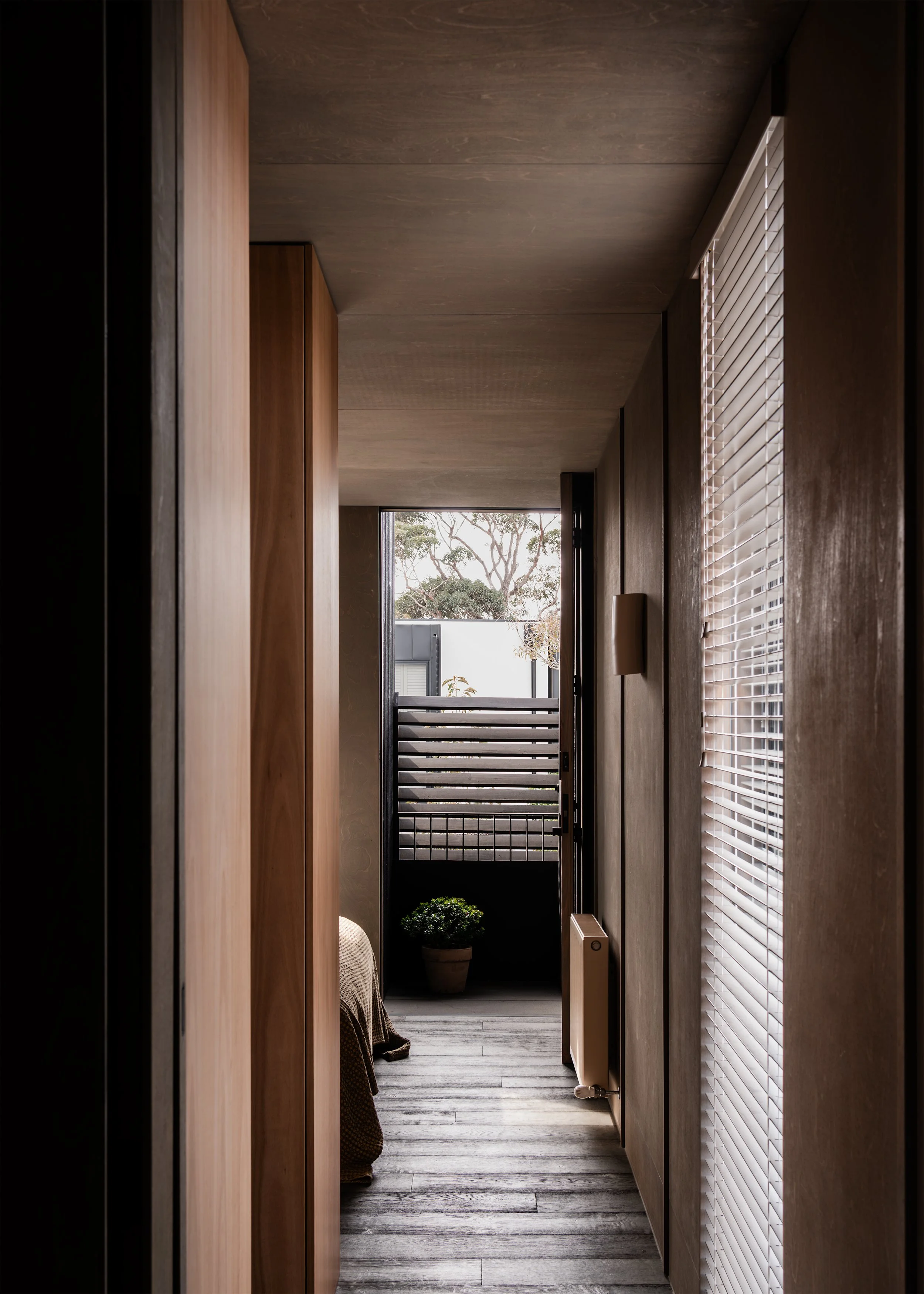 Upper-level corridor leading to a small balcony, main bedroom and framed treetop outlook in the Topology Studio addition.