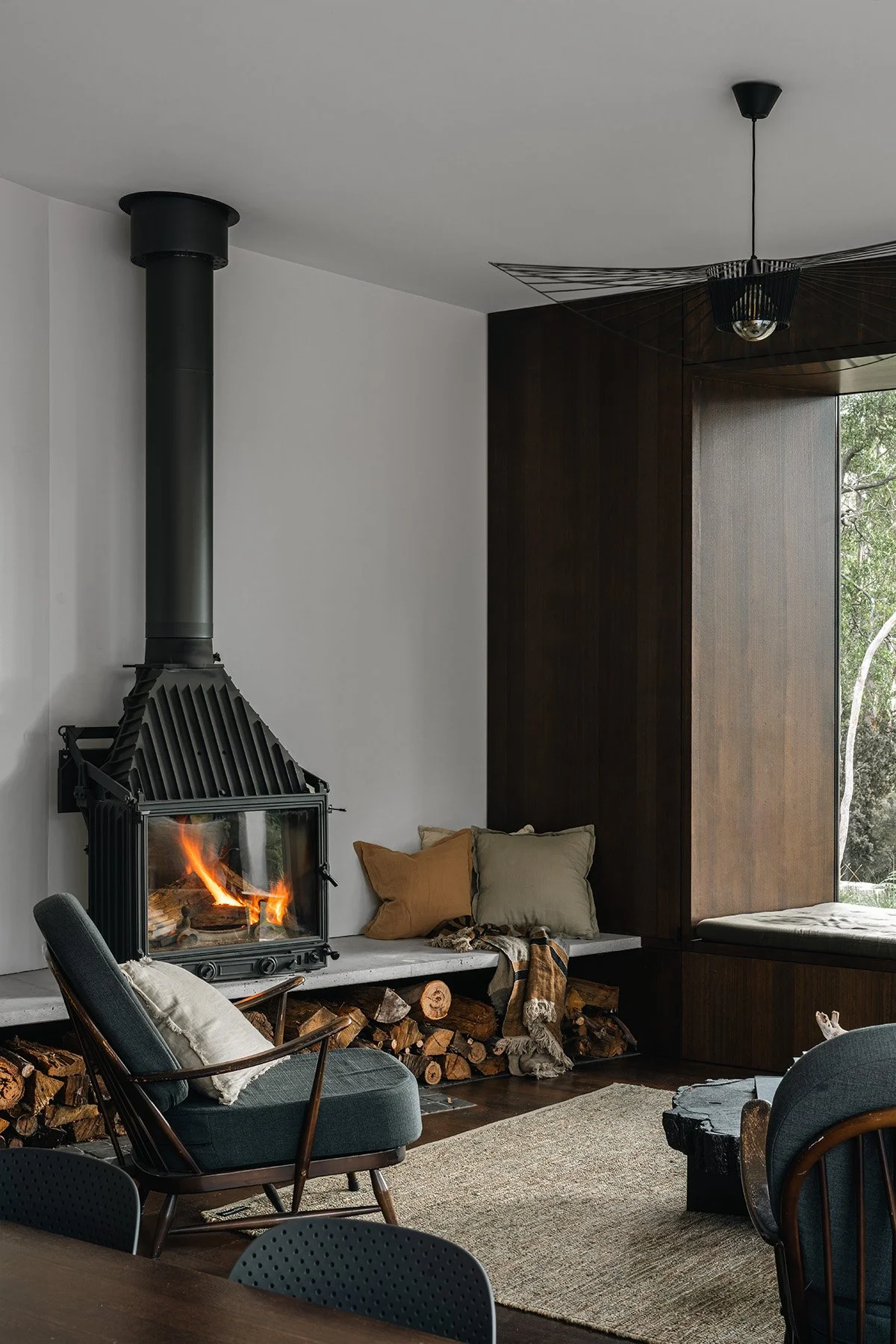 Living room at Killora Bay with a Cheminees Philippe fireplace, built-in concrete hearth and dark timber window surround.