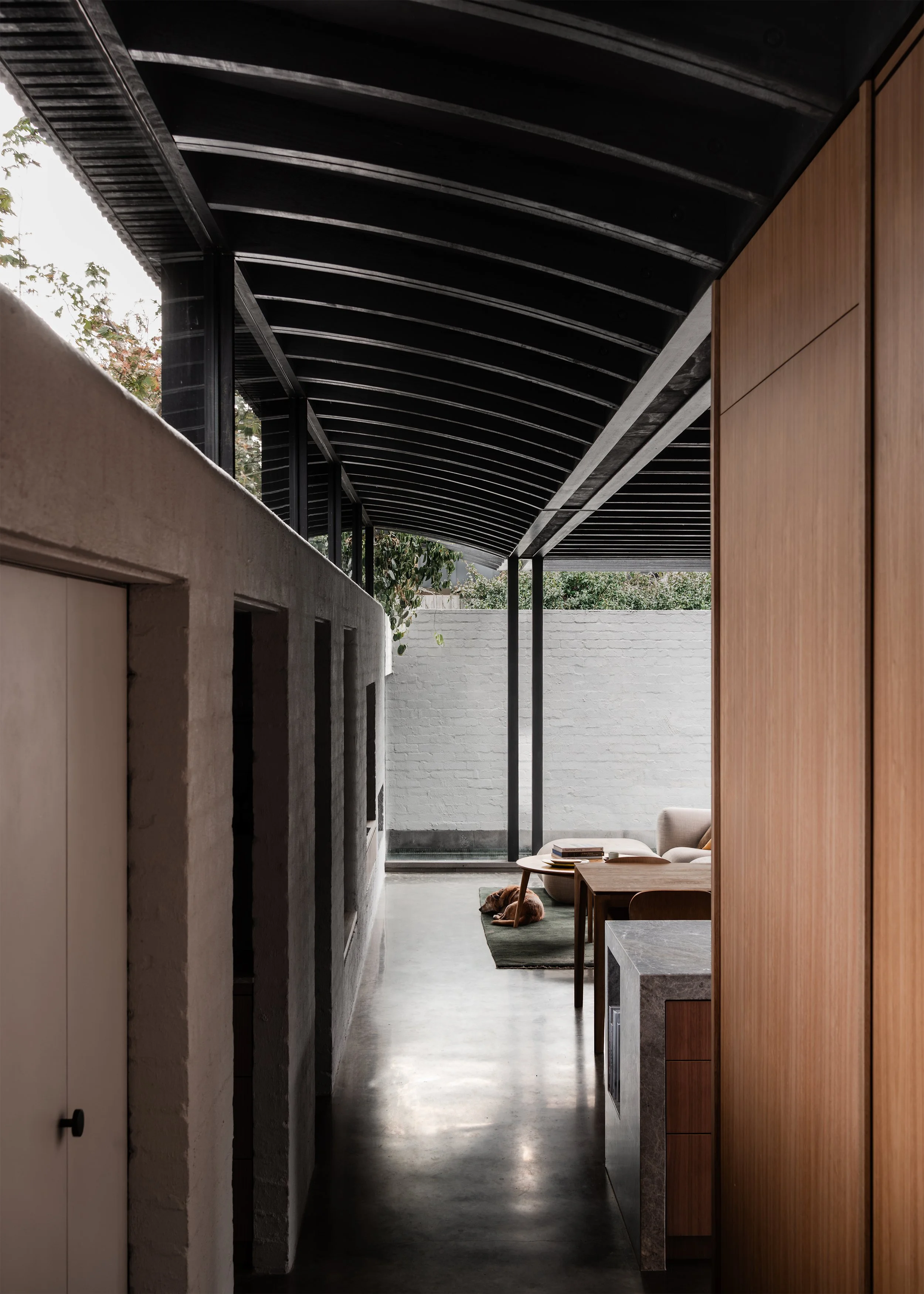 Long view through the kitchen and living pavilion toward the pool and high masonry garden wall.
