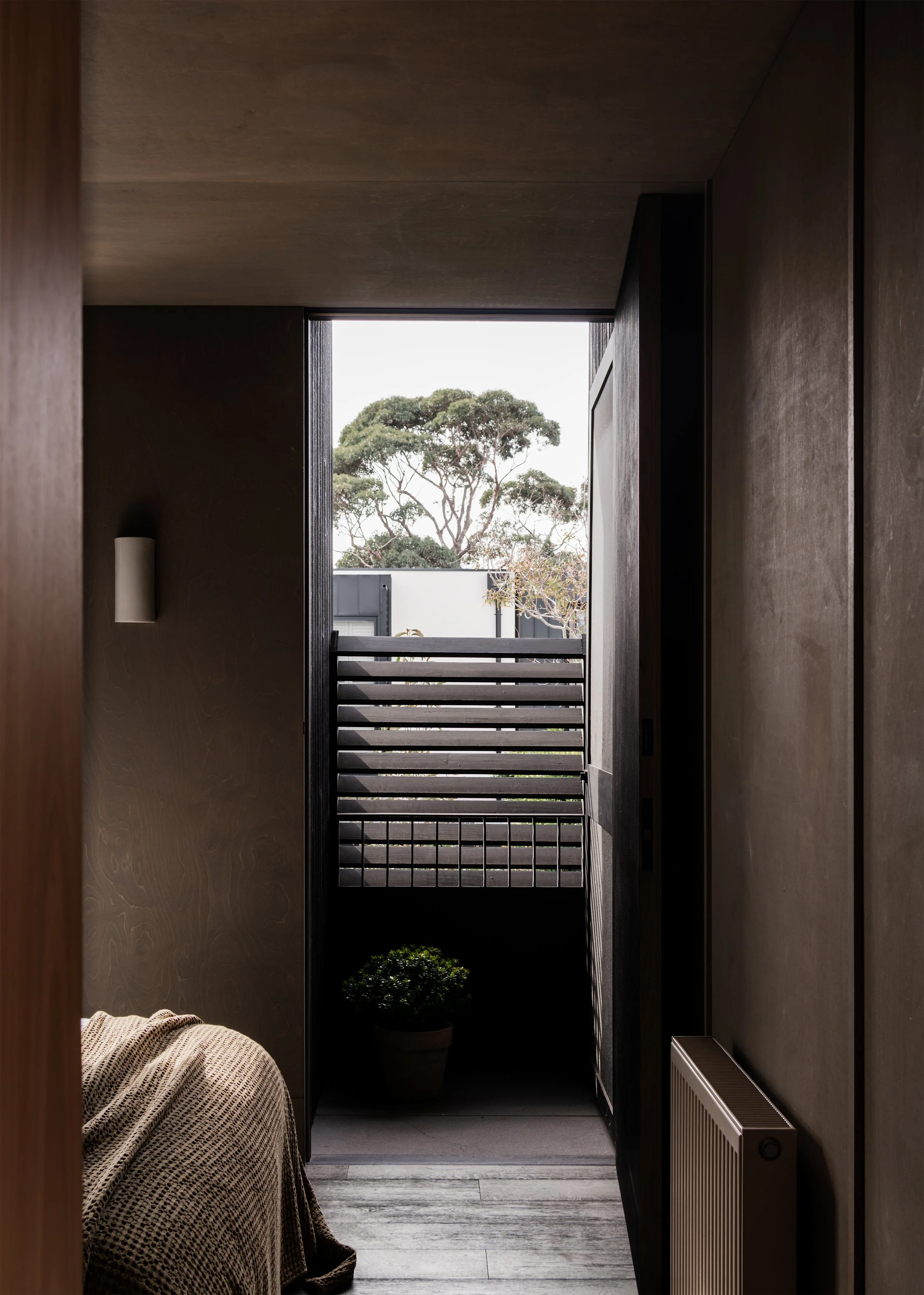Bedroom opening to a balcony and borrowed treetop view in this inner-Melbourne house extension.