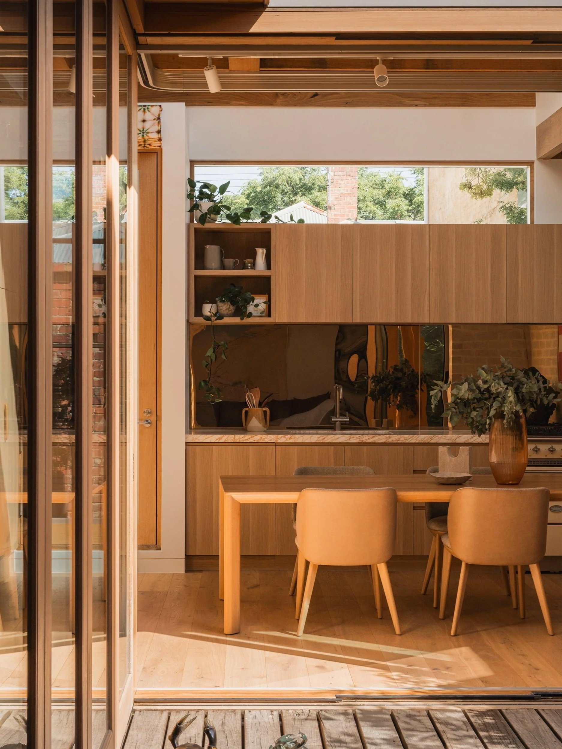 View from the courtyard into Little O’Grady’s timber-lined kitchen and dining area with a mirrored splashback.