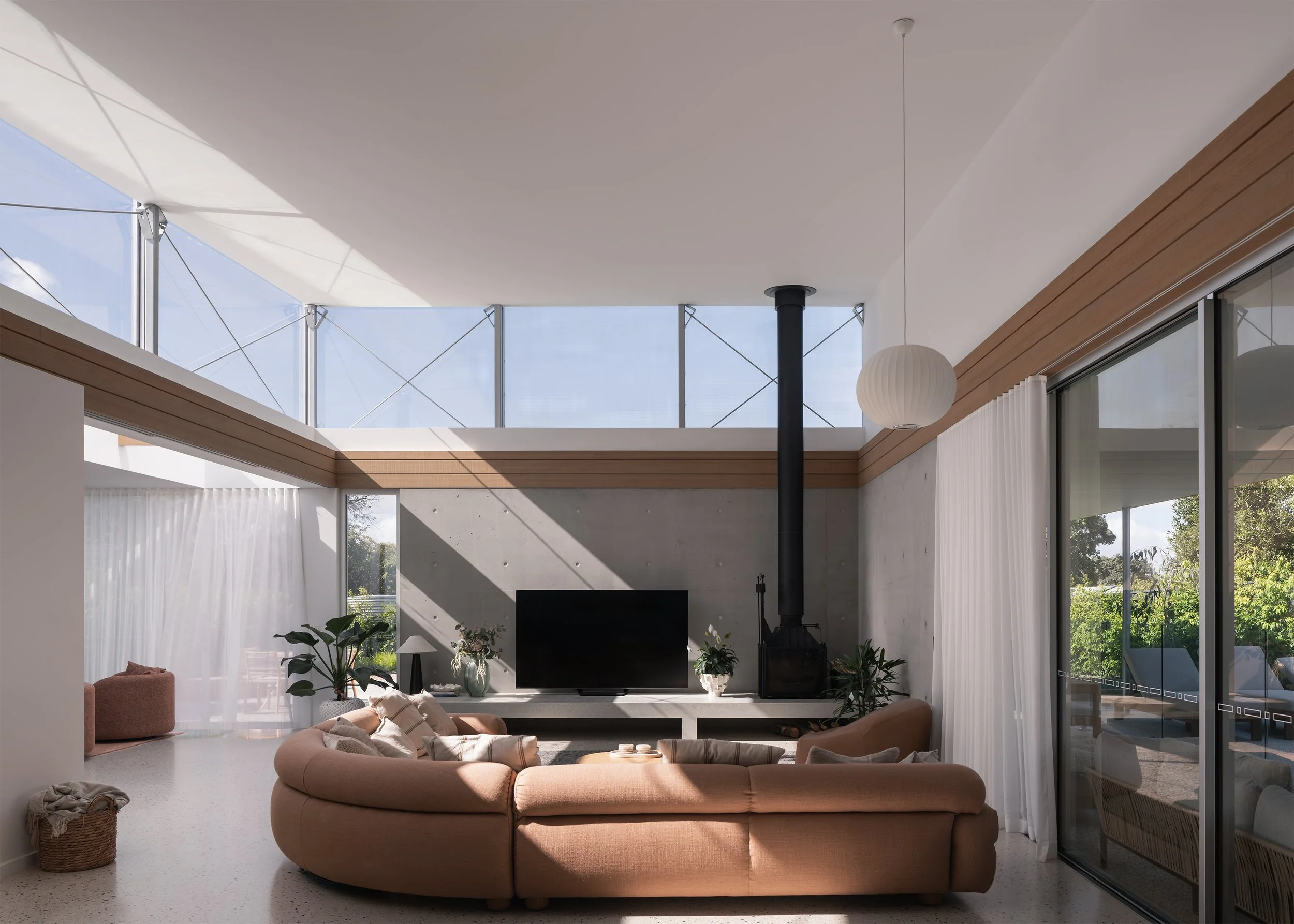 Living room with exposed concrete walls, clerestory glazing and garden views in Channel by Megowan Architectural.